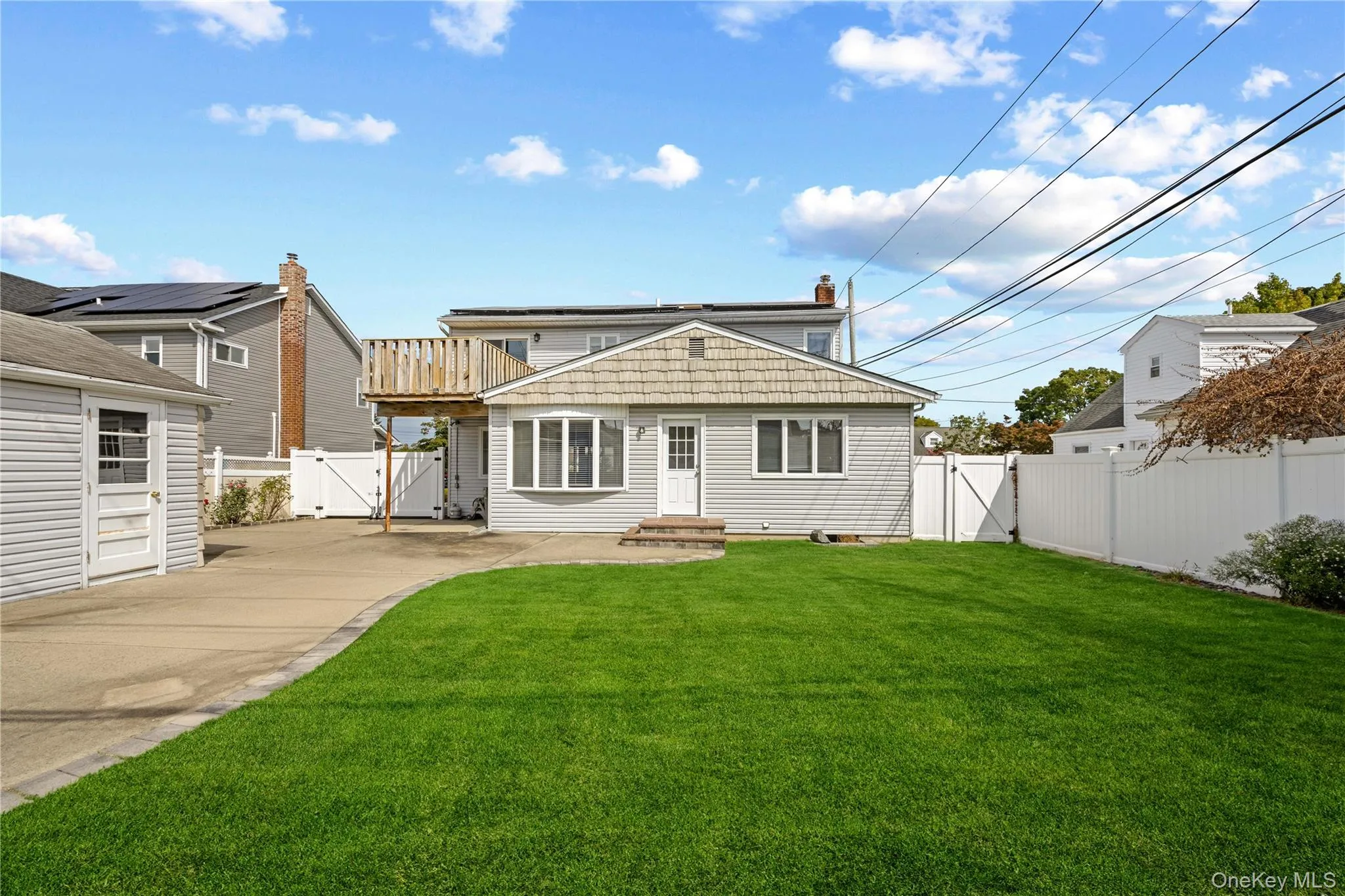 Expansive green lawn, white privacy fencing, paved driveway, detached garage, and a wood deck Expansive green lawn, white privacy fencing, paved driveway, detached garage, and a wood deck