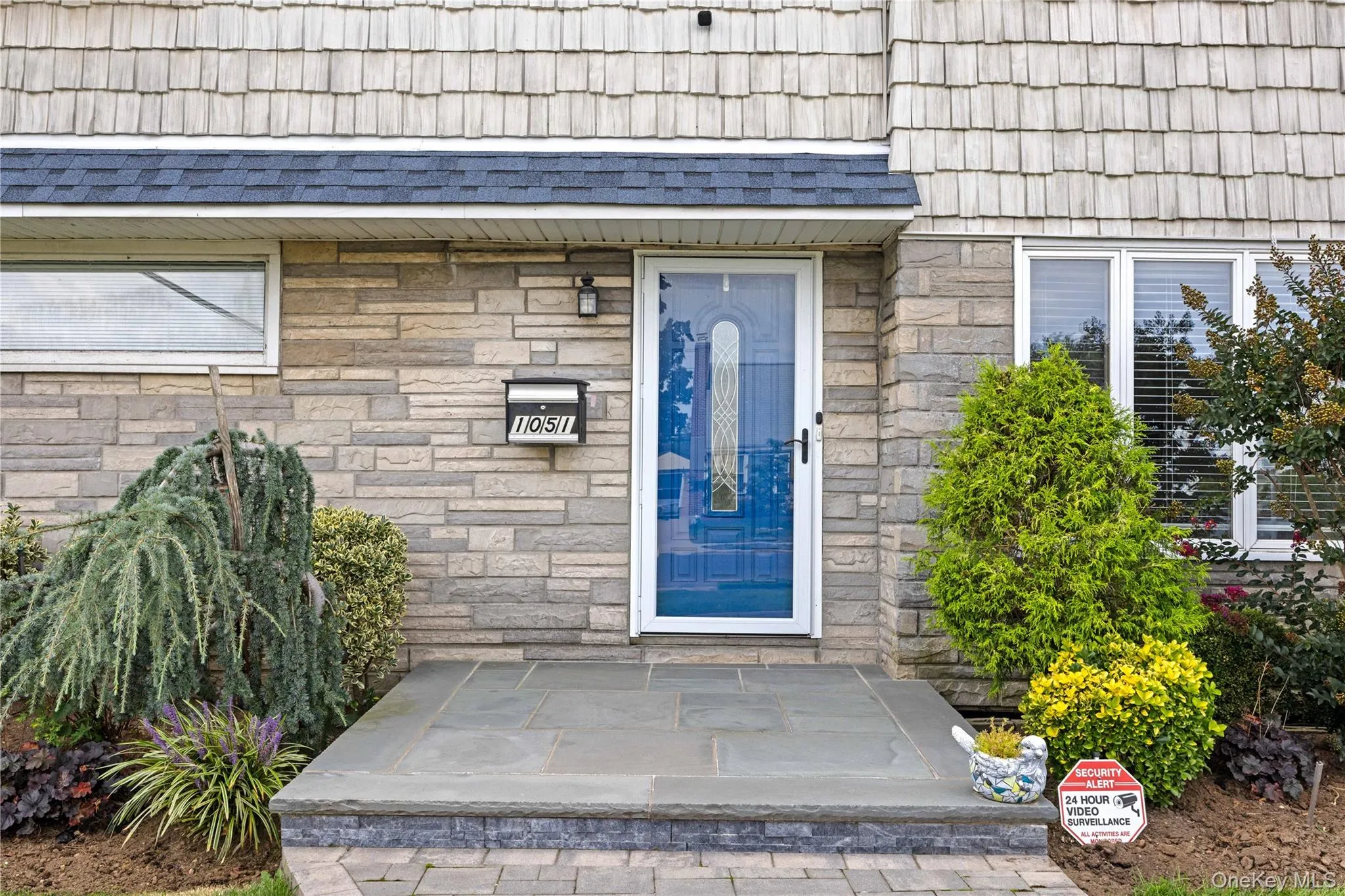 Stone veneer facade with cedar shake siding, natural stone porch, and a decorative glass storm door Stone veneer facade with cedar shake siding, natural stone porch, and a decorative glass storm door