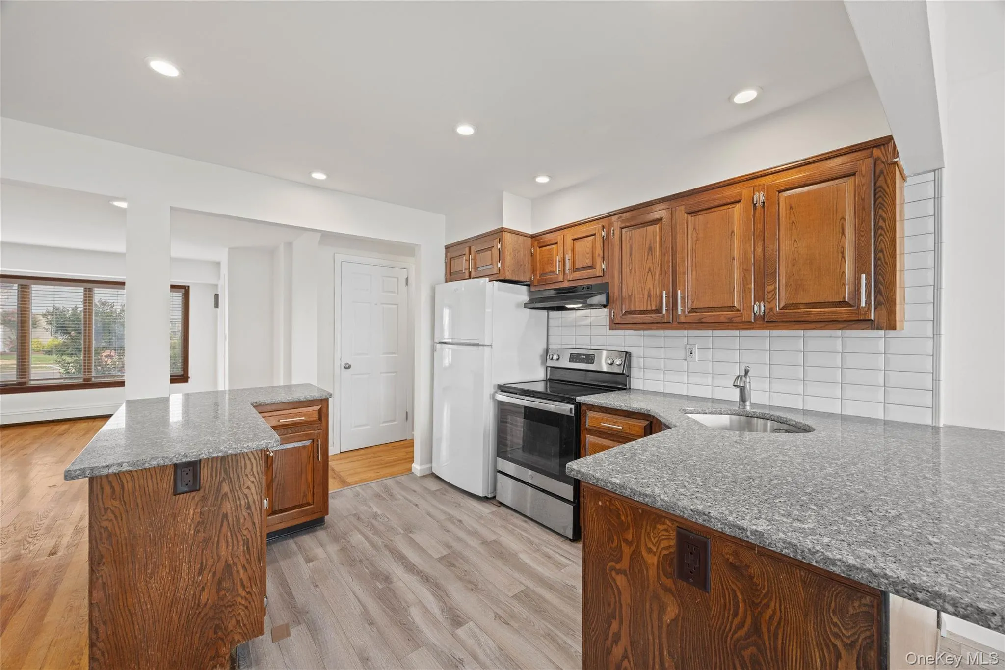 Kitchen featuring wood cabinetry, light-colored countertops, stainless steel appliances, and a tiled backsplash Kitchen featuring wood cabinetry, light-colored countertops, stainless steel appliances, and a tiled backsplash