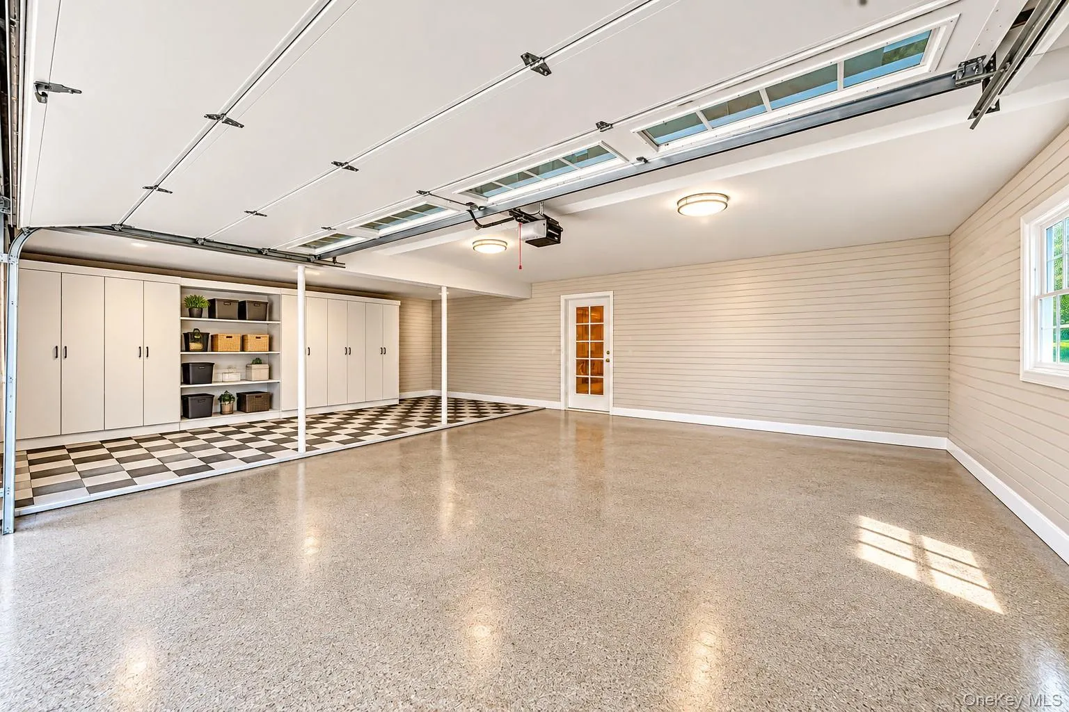 Epoxy-coated flooring, built-in cabinetry with open shelving, checkered flooring, a window, and an interior door with glass panels Epoxy-coated flooring, built-in cabinetry with open shelving, checkered flooring, a window, and an interior door with glass panels