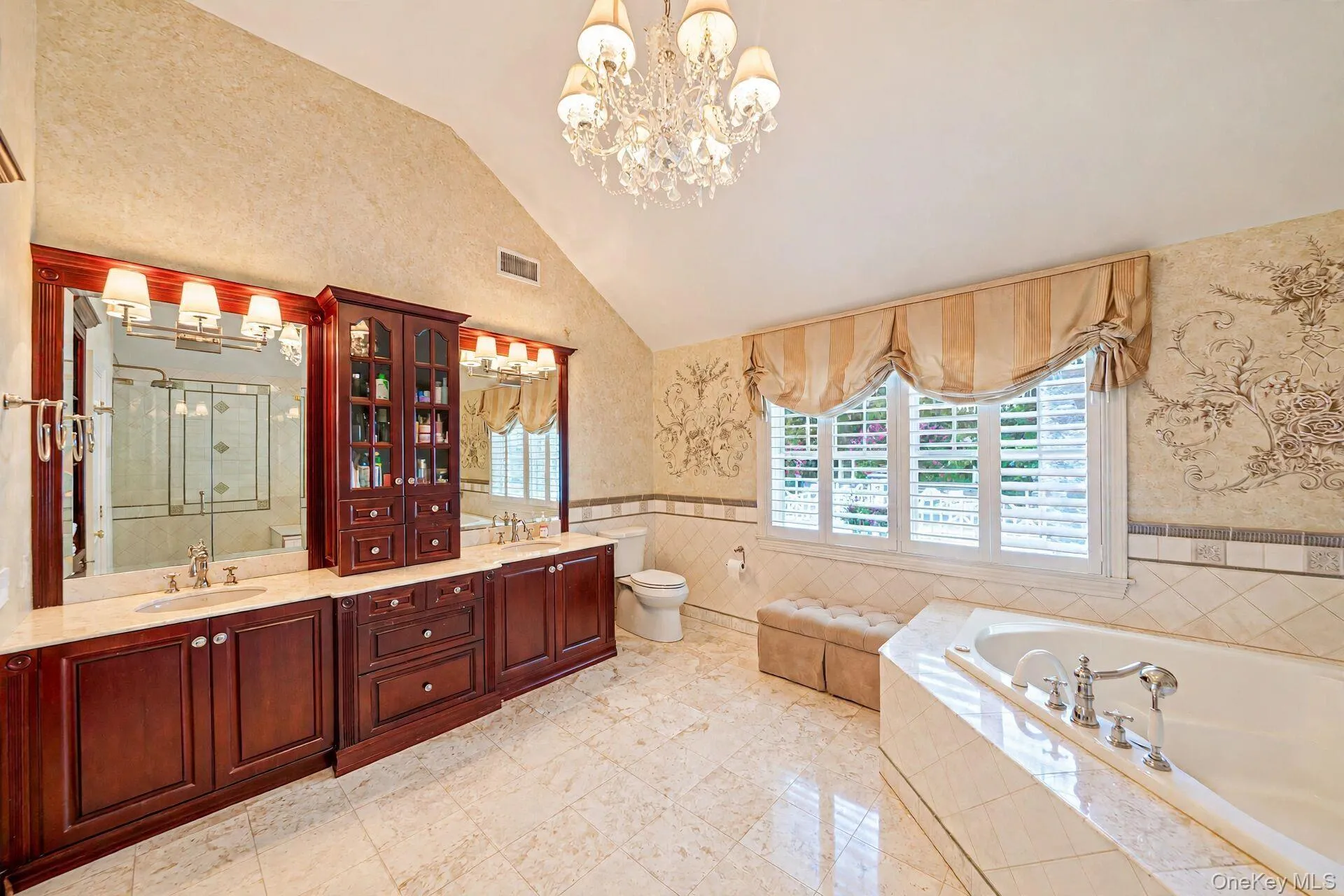 Vaulted ceiling with chandelier, extensive wood-finish cabinetry, dual vanity with undermount sinks, and a built-in tub Vaulted ceiling with chandelier, extensive wood-finish cabinetry, dual vanity with undermount sinks, and a built-in tub
