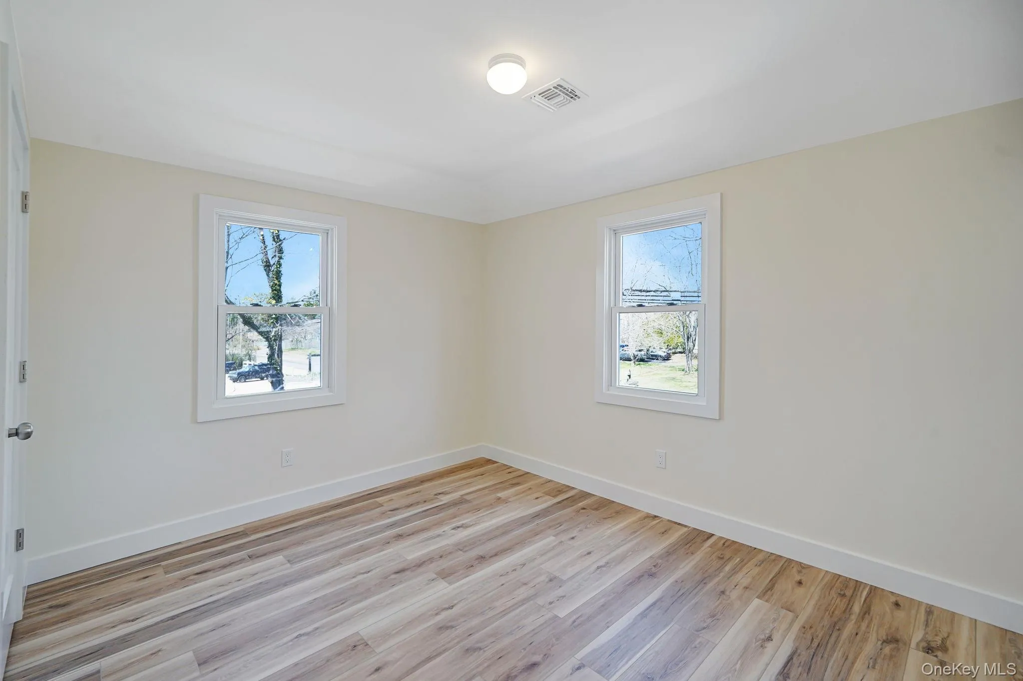 Empty room with light wood-type flooring and baseboards Empty room with light wood-type flooring and baseboards
