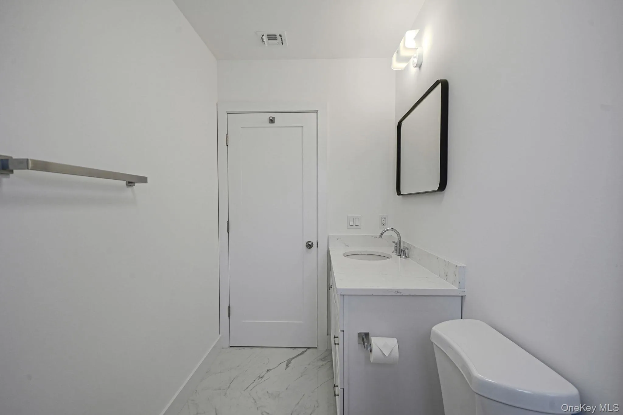 Bathroom with marble finish floors, vanity, toilet, and baseboards Bathroom with marble finish floors, vanity, toilet, and baseboards