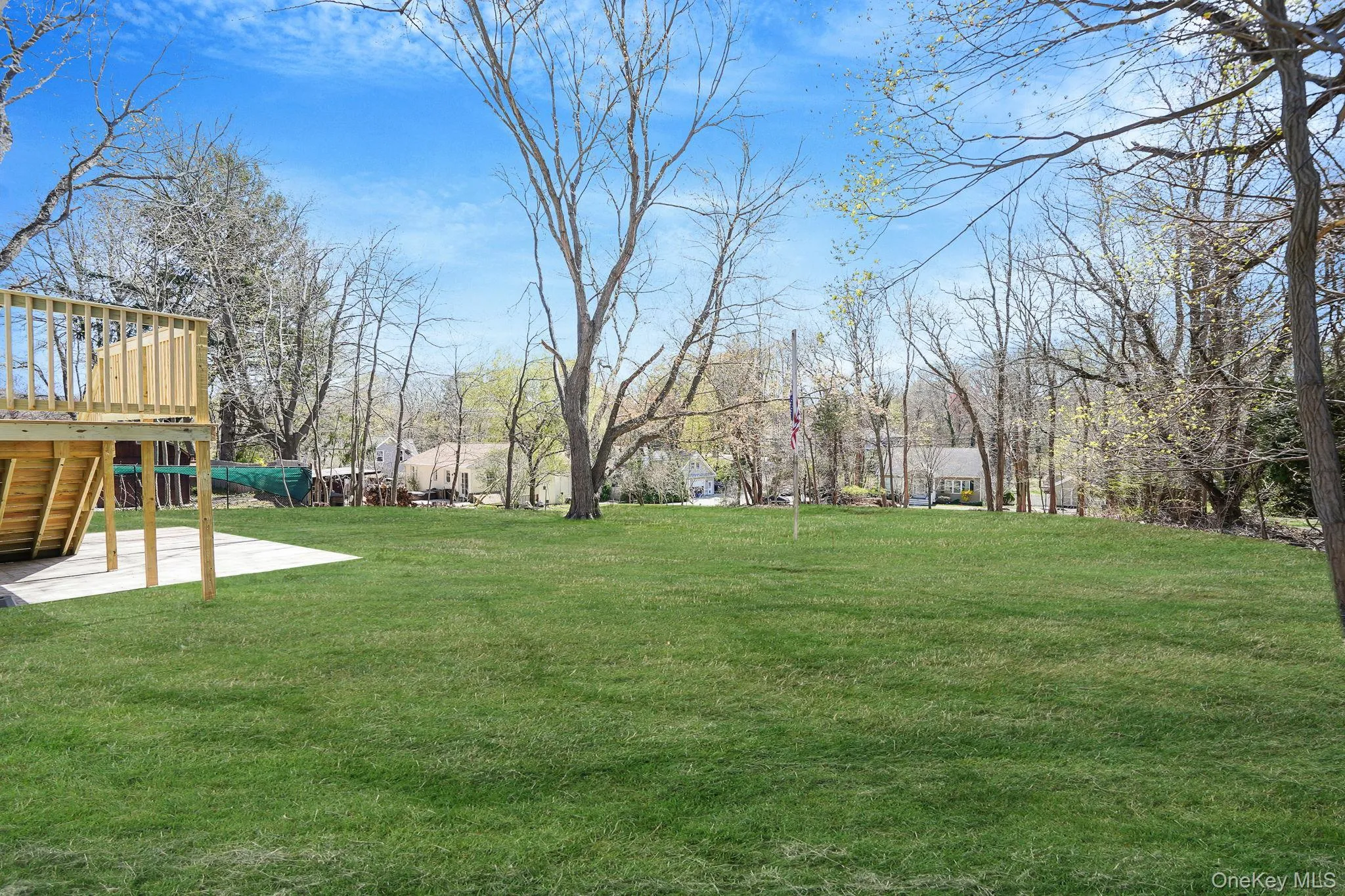 View of grassy yard featuring a wooden deck, stairs, and a patio View of grassy yard featuring a wooden deck, stairs, and a patio