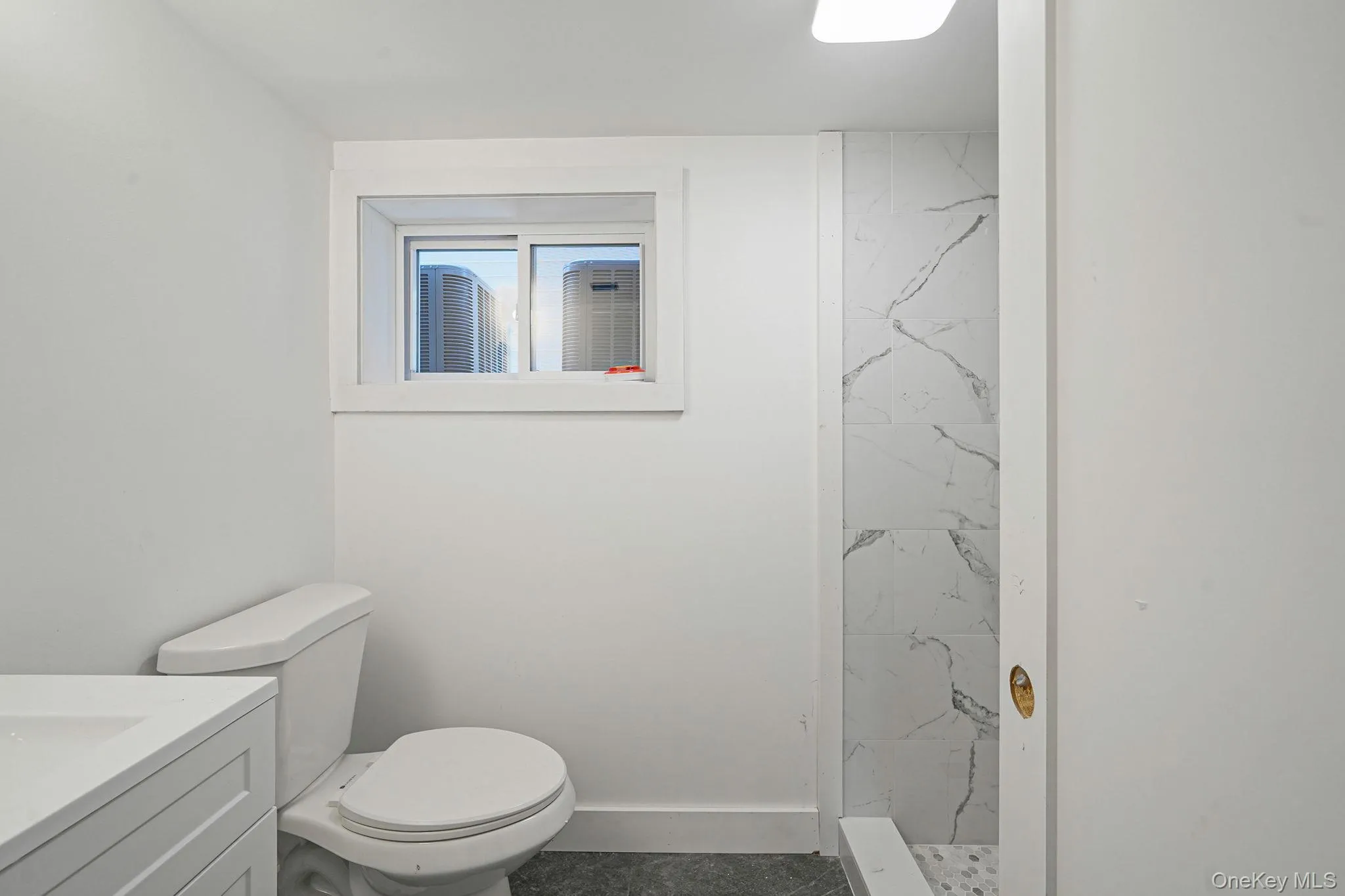 Full bathroom with vanity, a marble finish shower, toilet, and baseboards Full bathroom with vanity, a marble finish shower, toilet, and baseboards