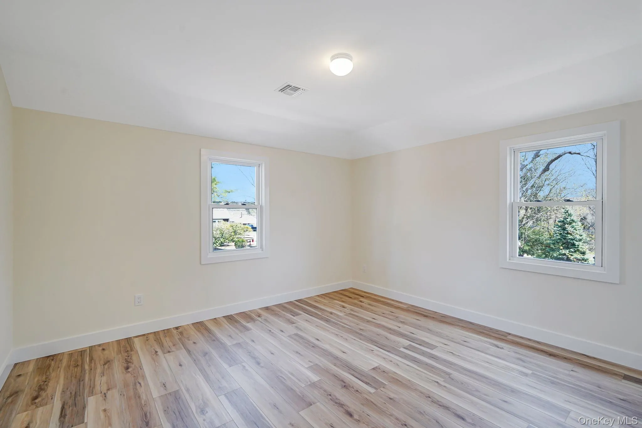 Spare room featuring healthy amount of natural light, light wood finished floors, and baseboards Spare room featuring healthy amount of natural light, light wood finished floors, and baseboards