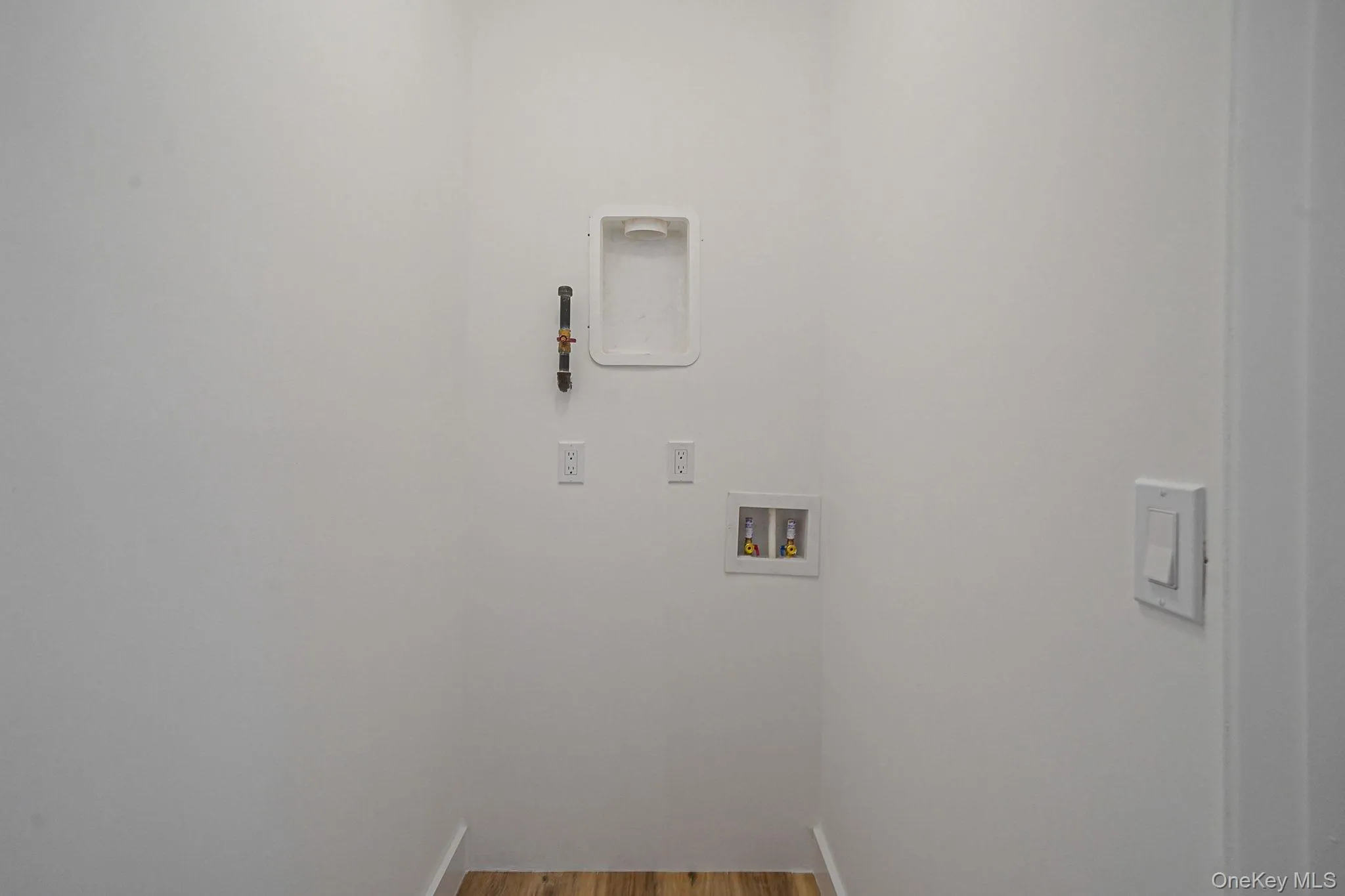 Washroom with hookup for a washing machine and wood finished floors Washroom with hookup for a washing machine and wood finished floors