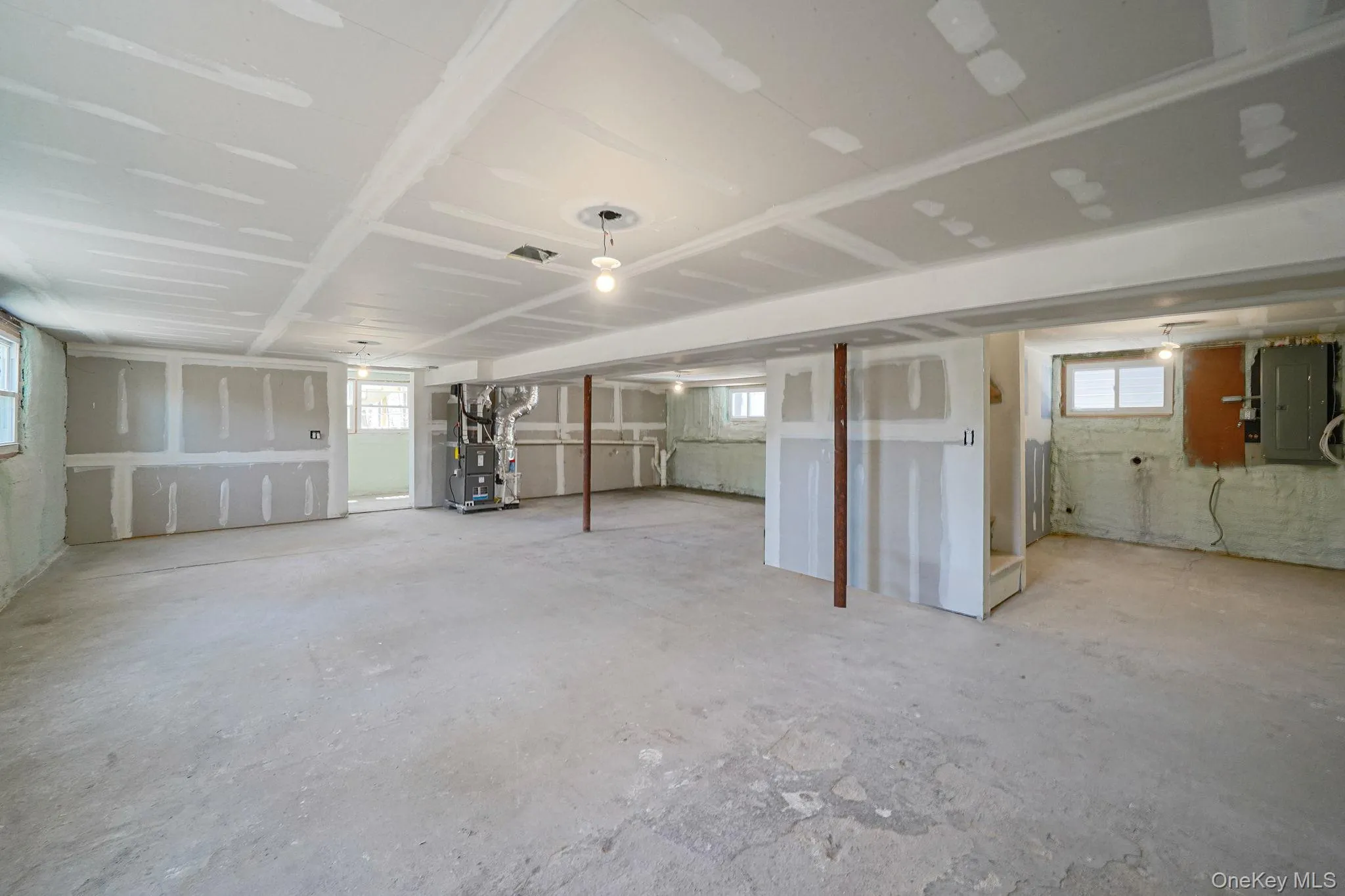 Basement with electric panel, heating unit, and healthy amount of natural light Basement with electric panel, heating unit, and healthy amount of natural light