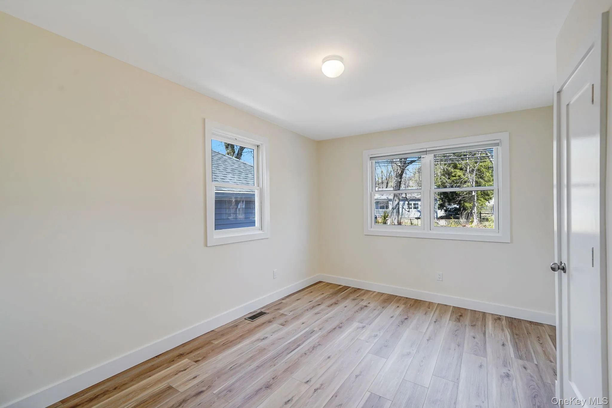 Spare room with plenty of natural light, baseboards, and light wood finished floors Spare room with plenty of natural light, baseboards, and light wood finished floors