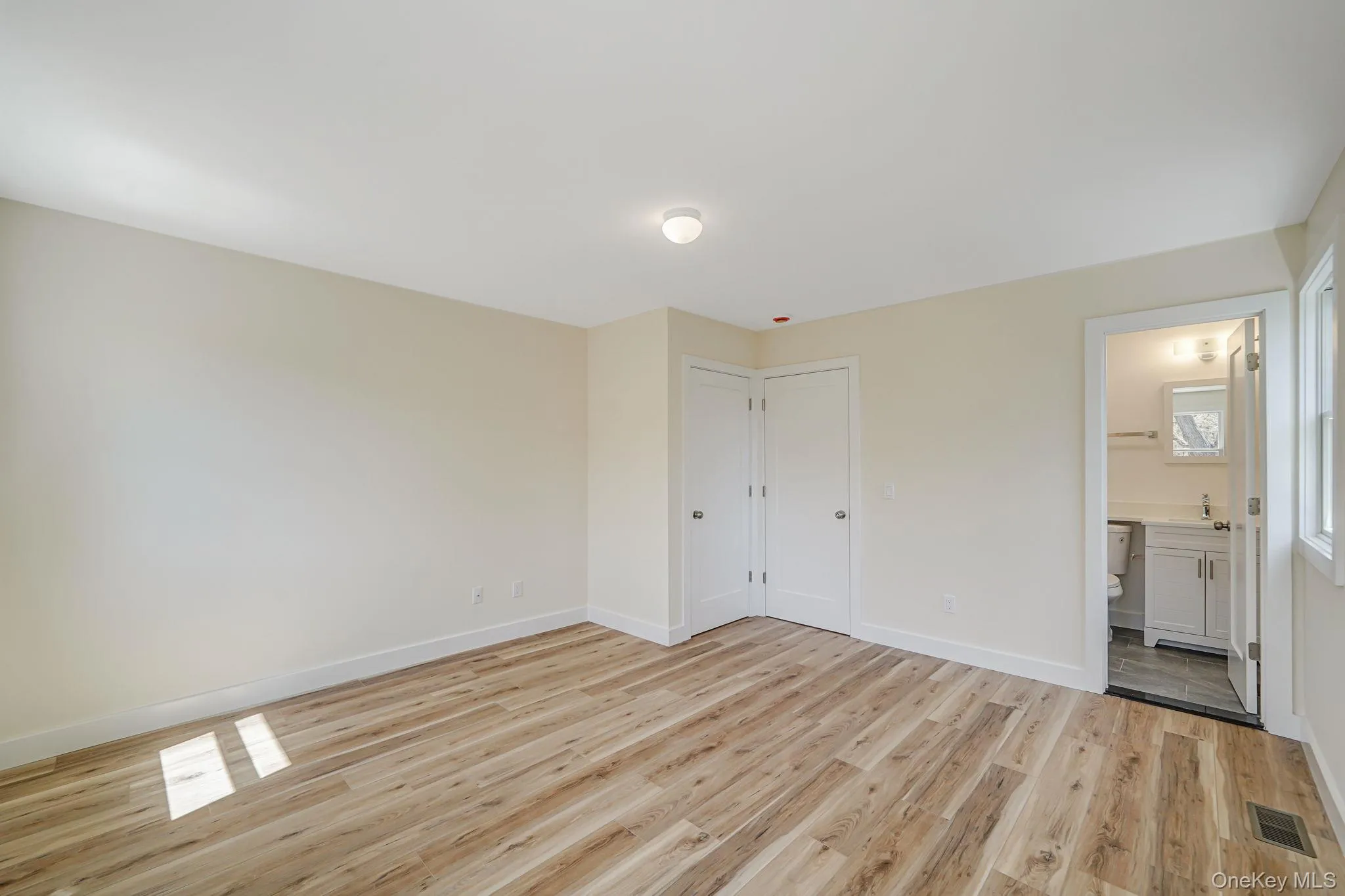 Unfurnished bedroom with light wood-type flooring, baseboards, connected bathroom, and a sink Unfurnished bedroom with light wood-type flooring, baseboards, connected bathroom, and a sink
