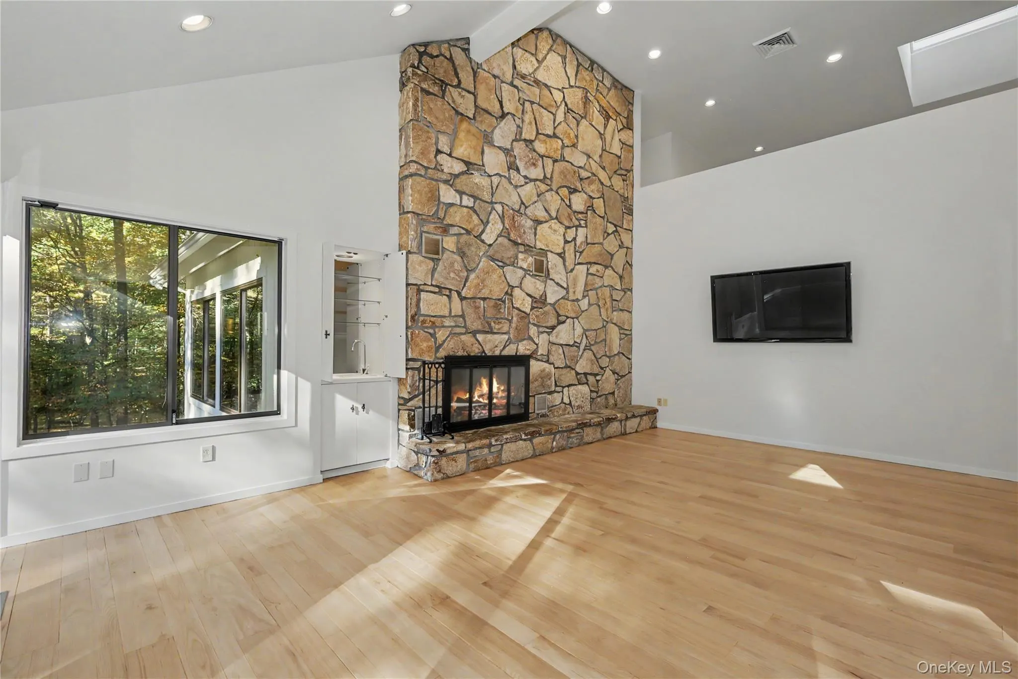Inviting family room with cathedral ceilings, skylights, and a striking stone fireplace extending to the ceiling. Inviting family room with cathedral ceilings, skylights, and a striking stone fireplace extending to the ceiling.