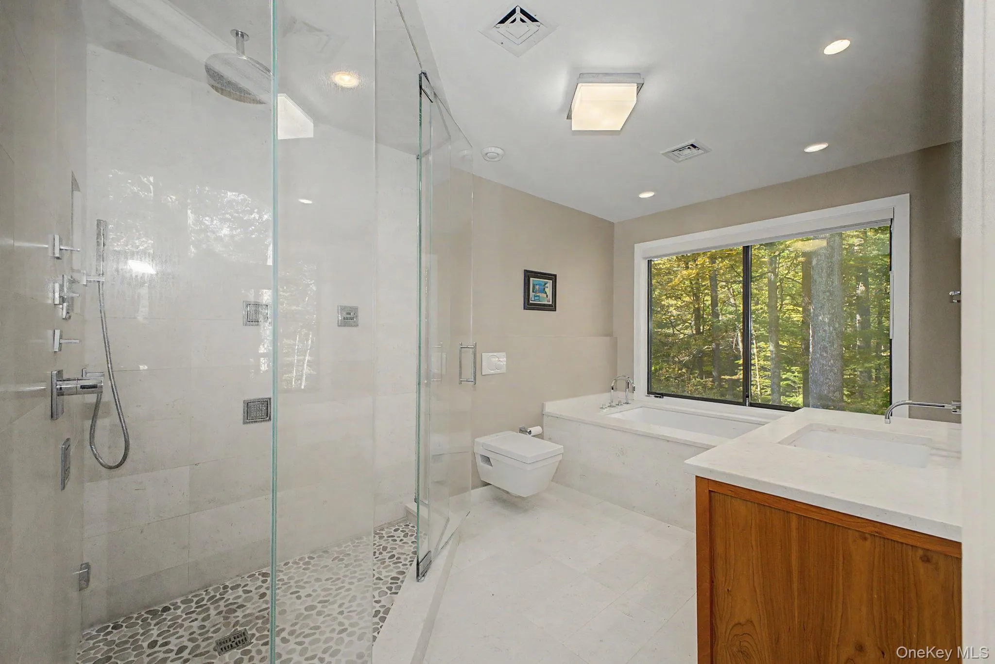 Light-filled primary bath with glass-enclosed steam shower, Bain Ultra tub, and serene woodland views. Light-filled primary bath with glass-enclosed steam shower, Bain Ultra tub, and serene woodland views.