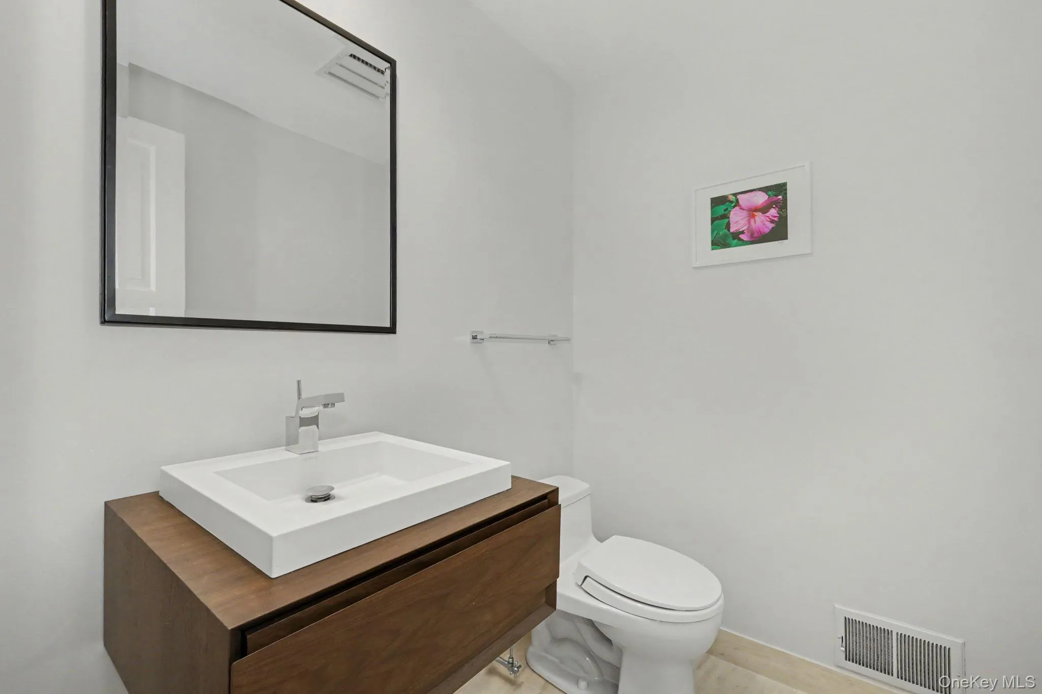 Powder room conveniently located near the office, featuring a floating wood vanity and a vessel sink. Powder room conveniently located near the office, featuring a floating wood vanity and a vessel sink.