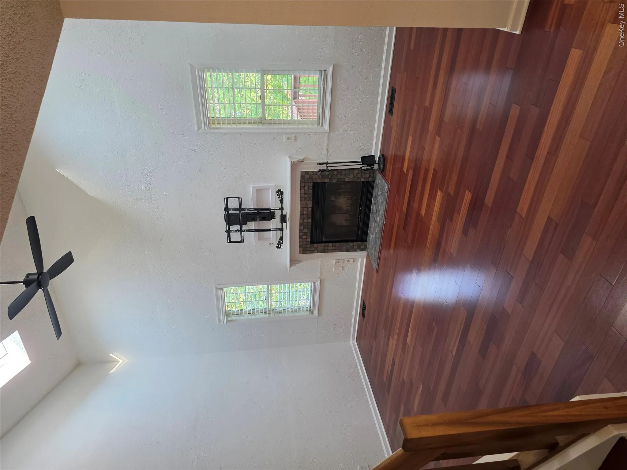Vaulted ceiling with skylight, dark wood-finish flooring, fireplace with stone surround, white mantel, and ceiling fan Vaulted ceiling with skylight, dark wood-finish flooring, fireplace with stone surround, white mantel, and ceiling fan