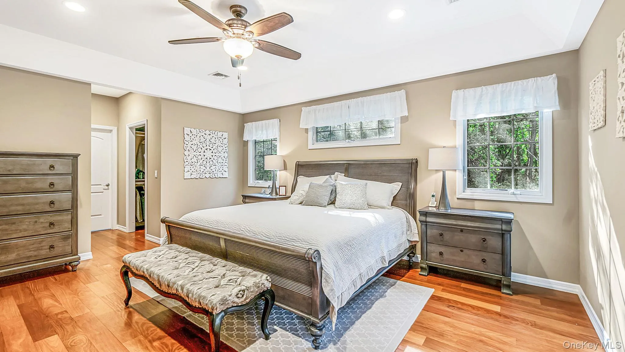 Tray ceiling with a ceiling fan, recessed lighting, and wood-finish flooring Tray ceiling with a ceiling fan, recessed lighting, and wood-finish flooring
