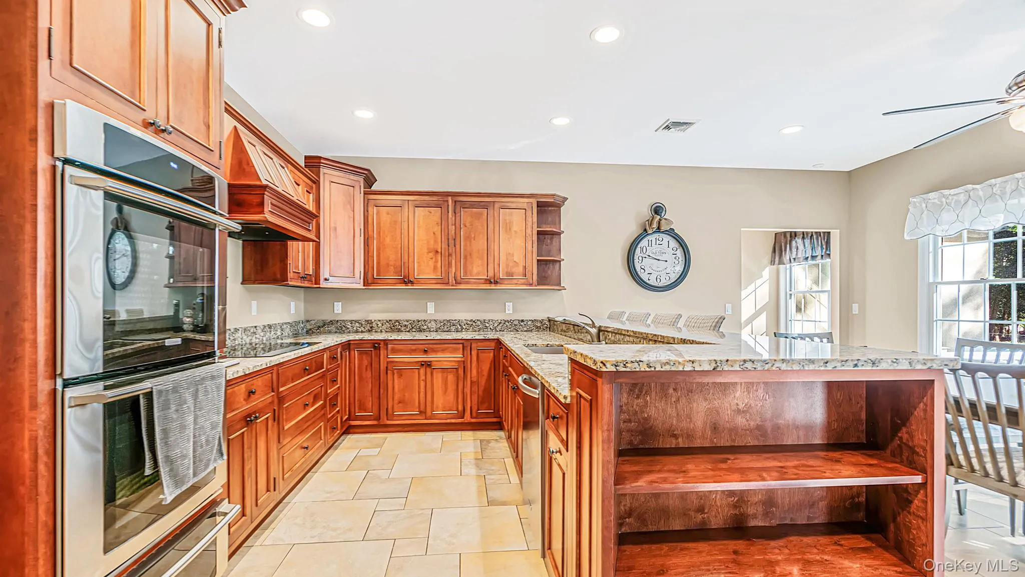 Kitchen featuring wood cabinetry, stone countertops, stainless steel appliances, and a breakfast bar Kitchen featuring wood cabinetry, stone countertops, stainless steel appliances, and a breakfast bar