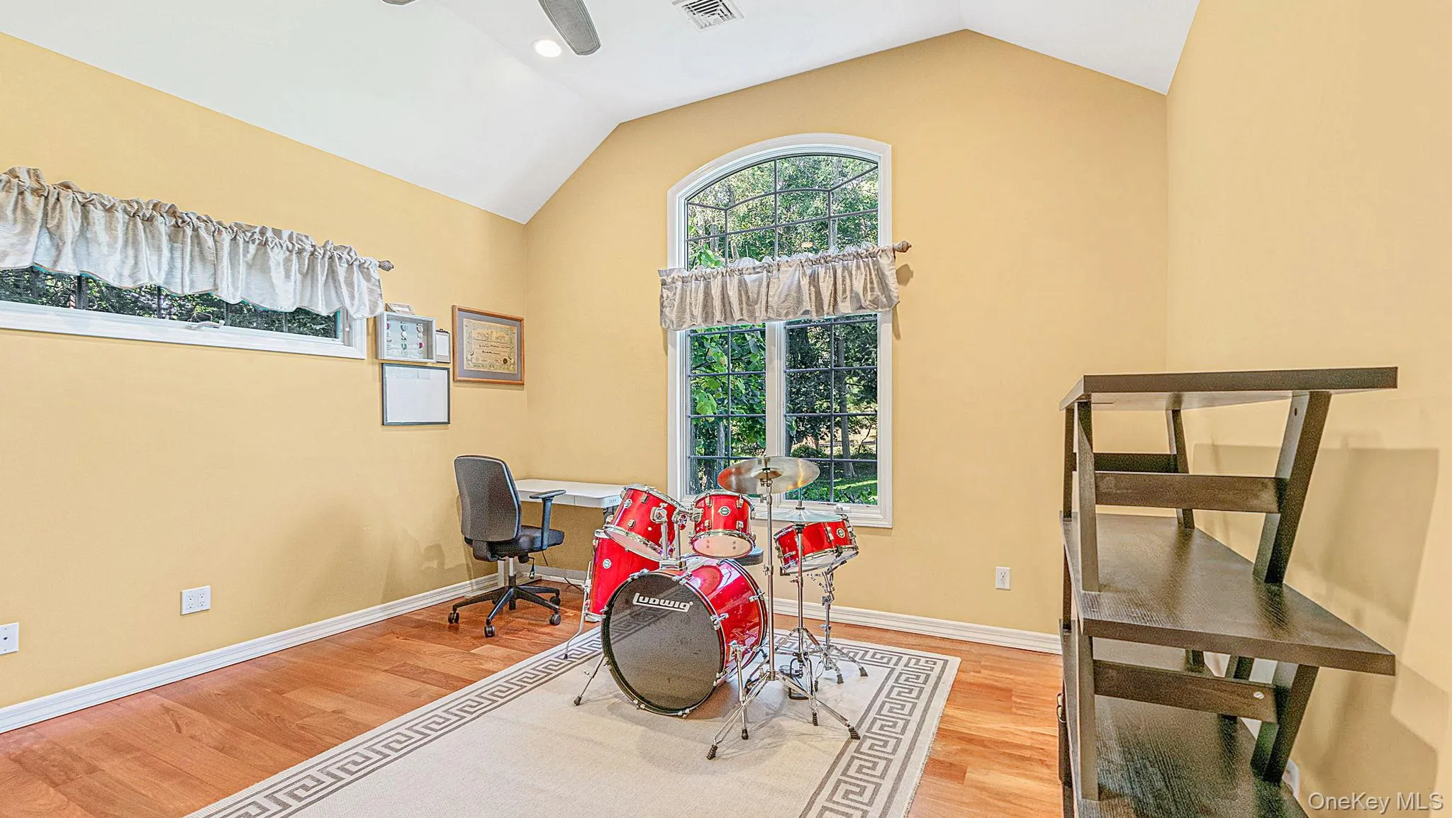 Vaulted ceiling with a ceiling fan, hardwood flooring, and an arched window Vaulted ceiling with a ceiling fan, hardwood flooring, and an arched window