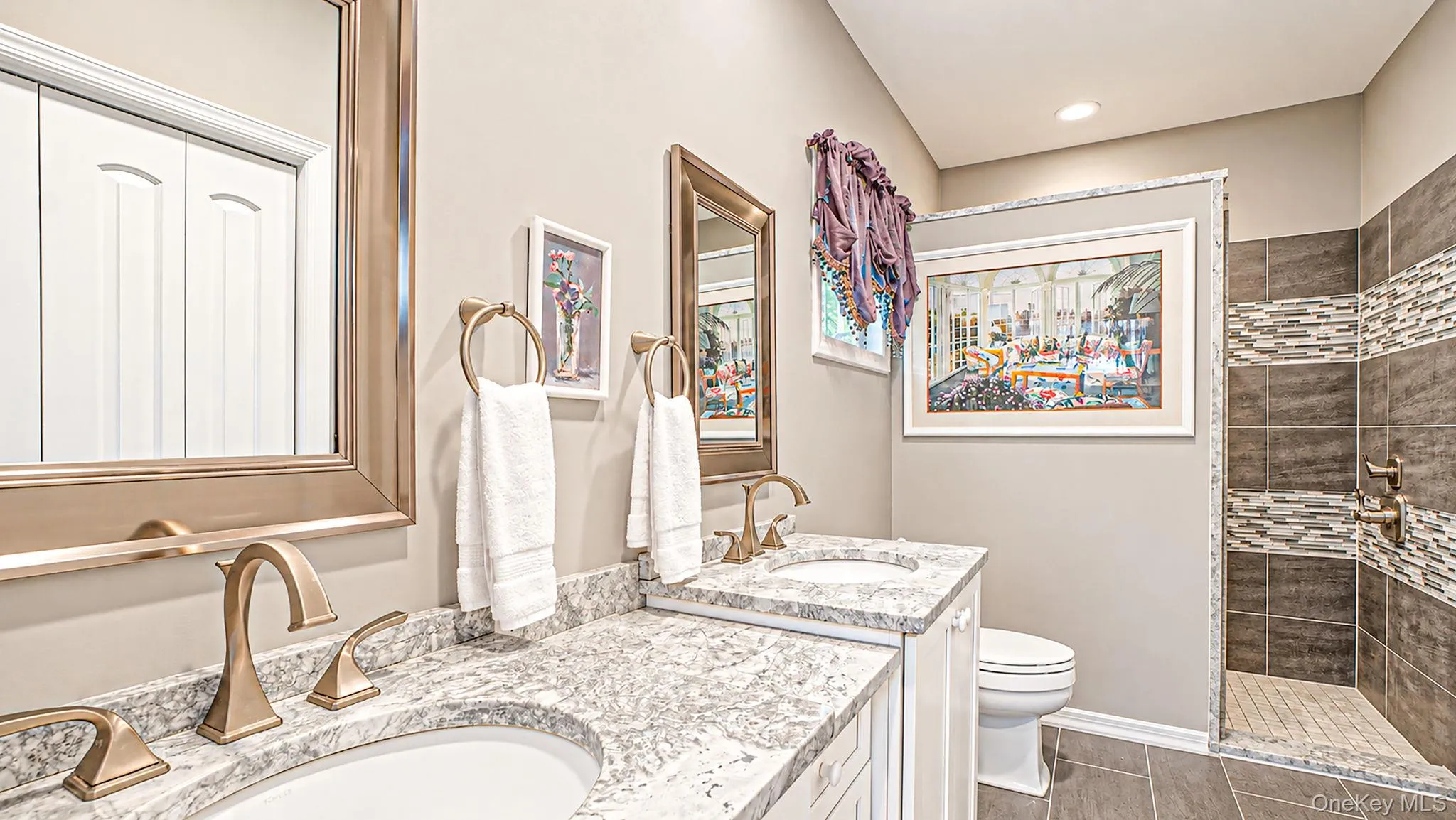 Spa-inspired master bathroom featuring dual vanities with polished stone countertops, brass fixtures, and an undermount sink design - radiant heated floors Spa-inspired master bathroom featuring dual vanities with polished stone countertops, brass fixtures, and an undermount sink design - radiant heated floors
