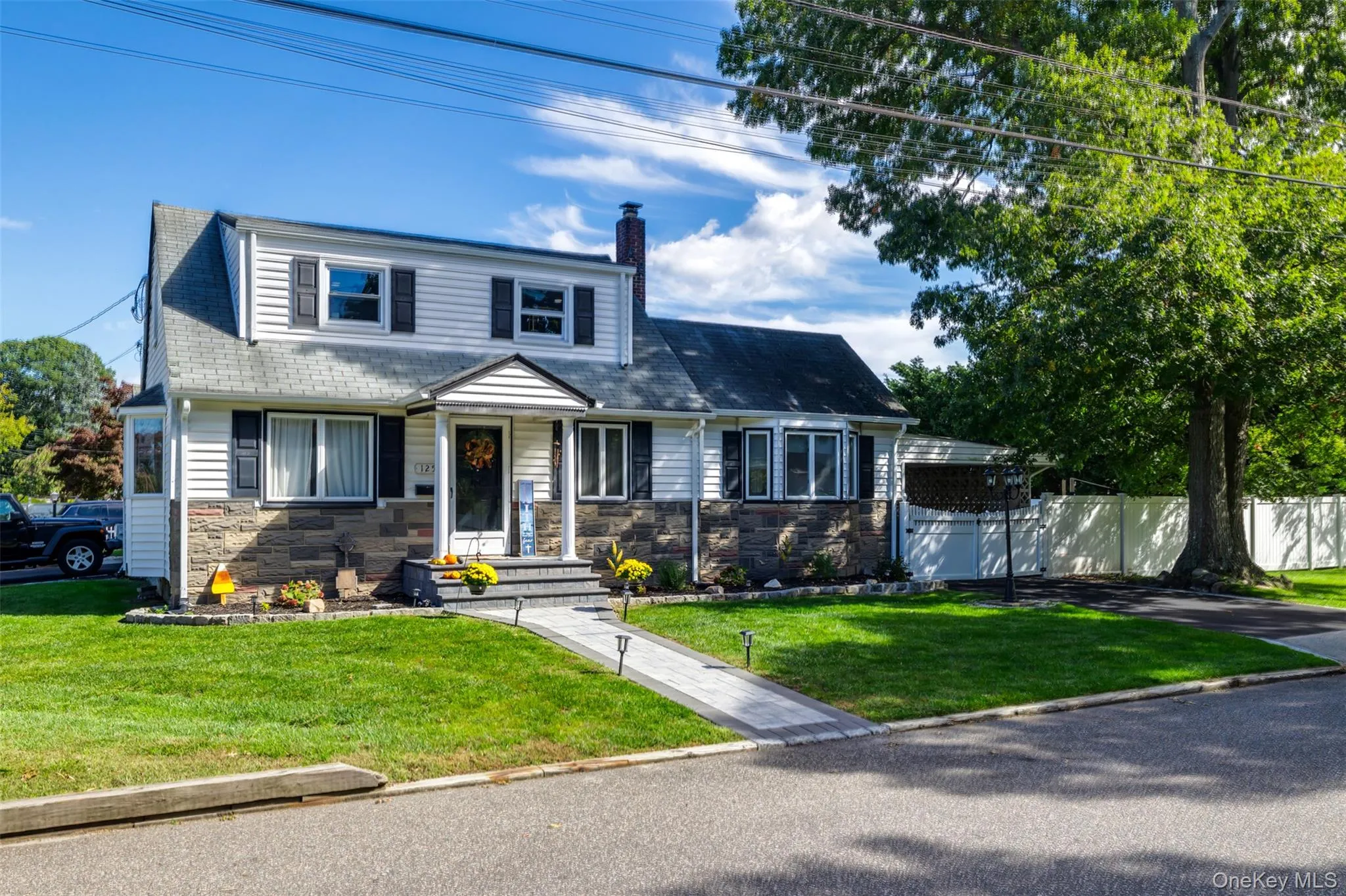 Two-story residence featuring stone and siding exterior, a gabled entry, bay window, and a paved walkway Two-story residence featuring stone and siding exterior, a gabled entry, bay window, and a paved walkway