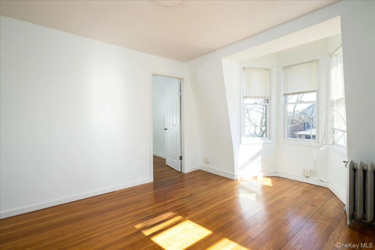 Second Floor Livingroom featuring wood-finish flooring, a three-paneled bay window, and a cast-iron radiator Second Floor Livingroom featuring wood-finish flooring, a three-paneled bay window, and a cast-iron radiator
