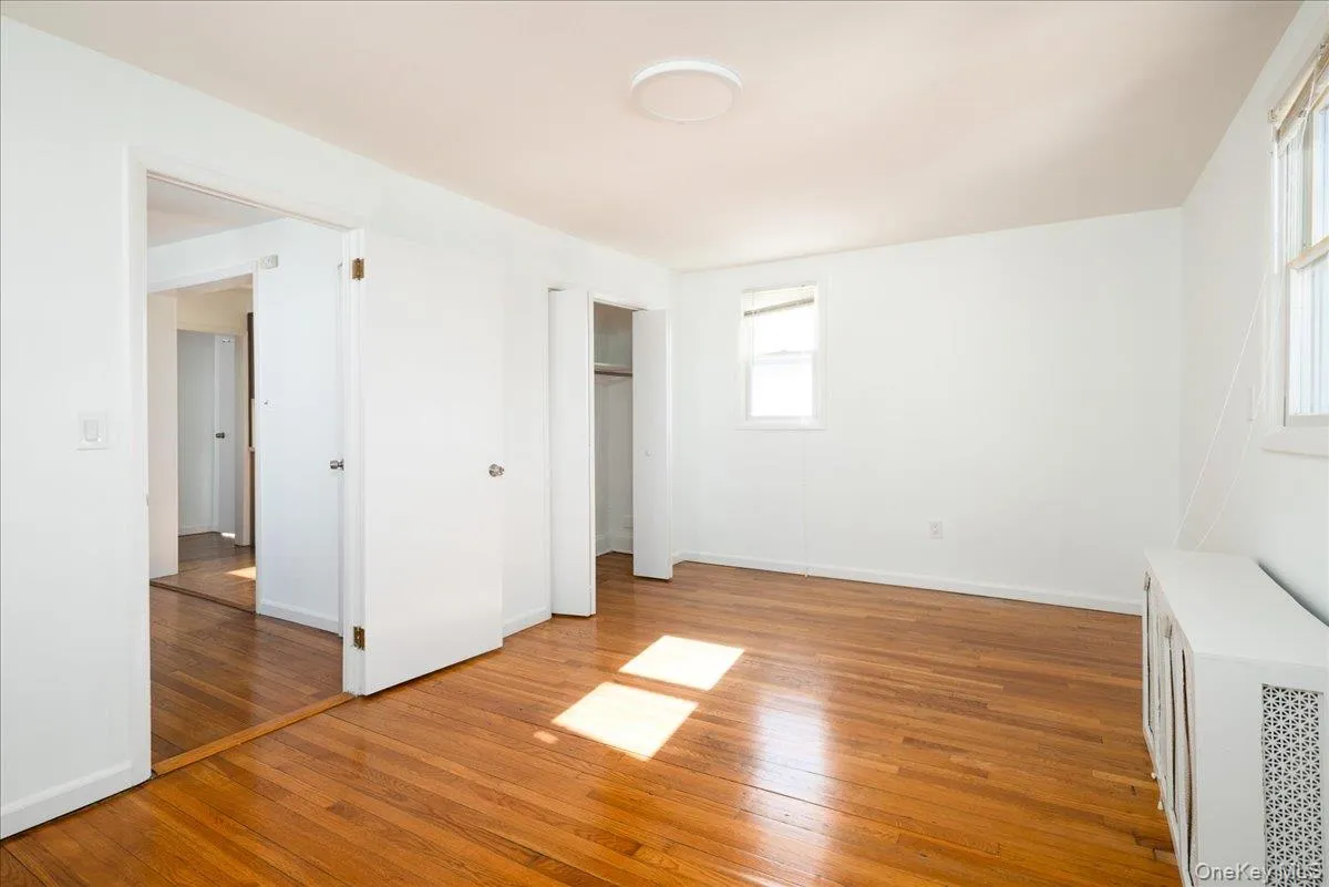 Second Floor Bedroom Wood-finish flooring, white walls, built-in closet with folding doors, and flush-mount ceiling lighting Second Floor Bedroom Wood-finish flooring, white walls, built-in closet with folding doors, and flush-mount ceiling lighting