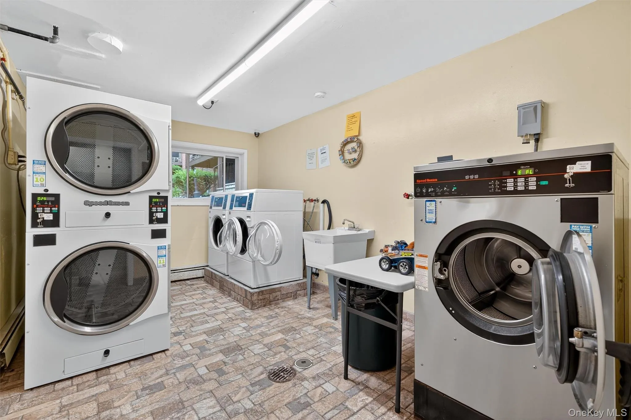 Laundry facility featuring multiple machines, durable flooring, and a utility sink Laundry facility featuring multiple machines, durable flooring, and a utility sink