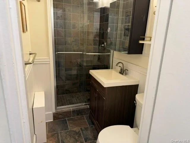 Walk-in shower with dark tile surround and glass enclosure Walk-in shower with dark tile surround and glass enclosure