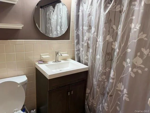 Bathroom featuring a dark wood-finish vanity with an integrated white sink, brushed nickel faucet, and a round wall-mounted mirror Bathroom featuring a dark wood-finish vanity with an integrated white sink, brushed nickel faucet, and a round wall-mounted mirror