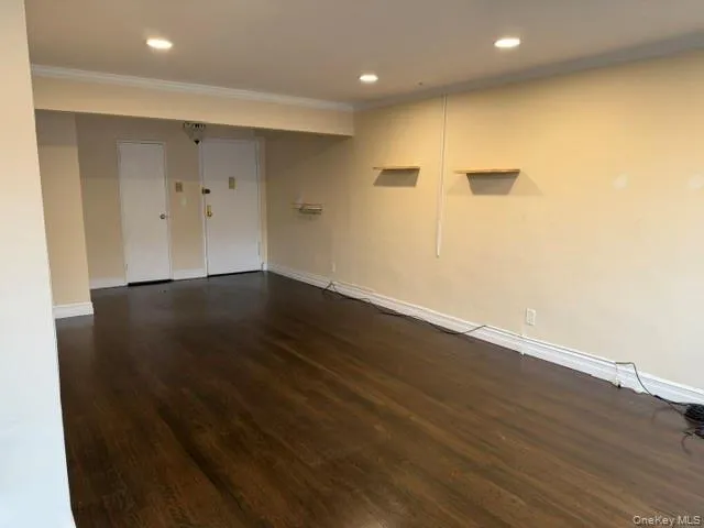 Dark wood-finish flooring, recessed ceiling lighting, crown molding, and two wall-mounted shelves Dark wood-finish flooring, recessed ceiling lighting, crown molding, and two wall-mounted shelves