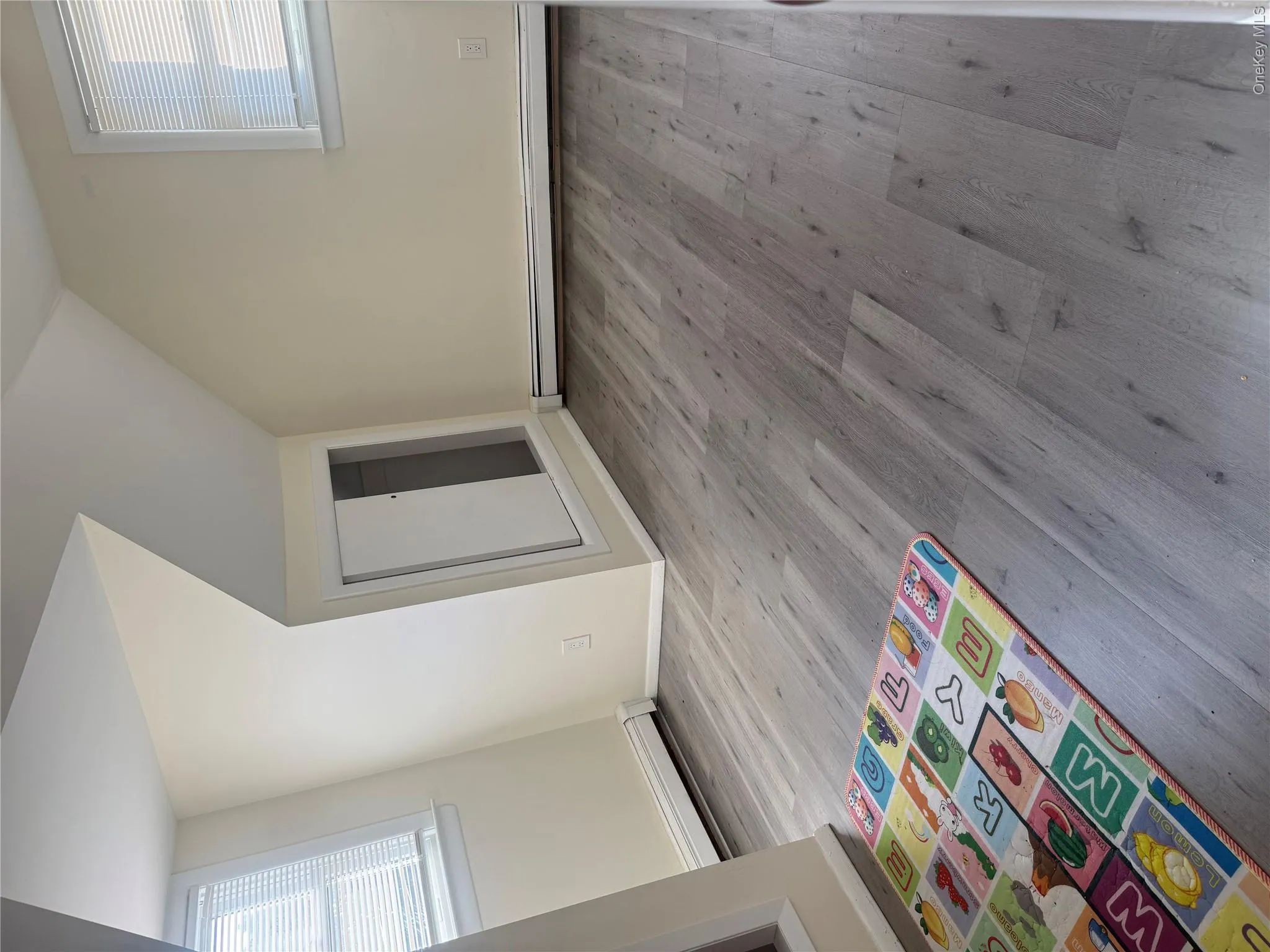 Wood-finish flooring with white baseboards, windows with blinds, and built-in storage with sliding doors Wood-finish flooring with white baseboards, windows with blinds, and built-in storage with sliding doors