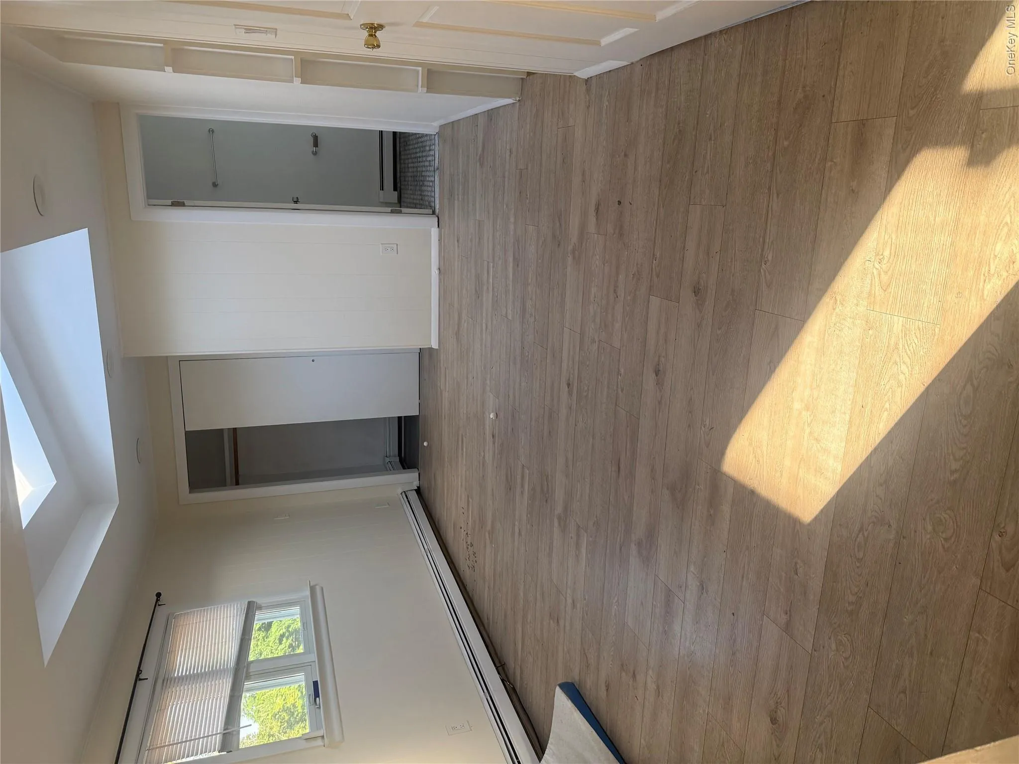 Skylight feature, wood-finish flooring, built-in shelving, window with blinds, and sliding closet doors Skylight feature, wood-finish flooring, built-in shelving, window with blinds, and sliding closet doors