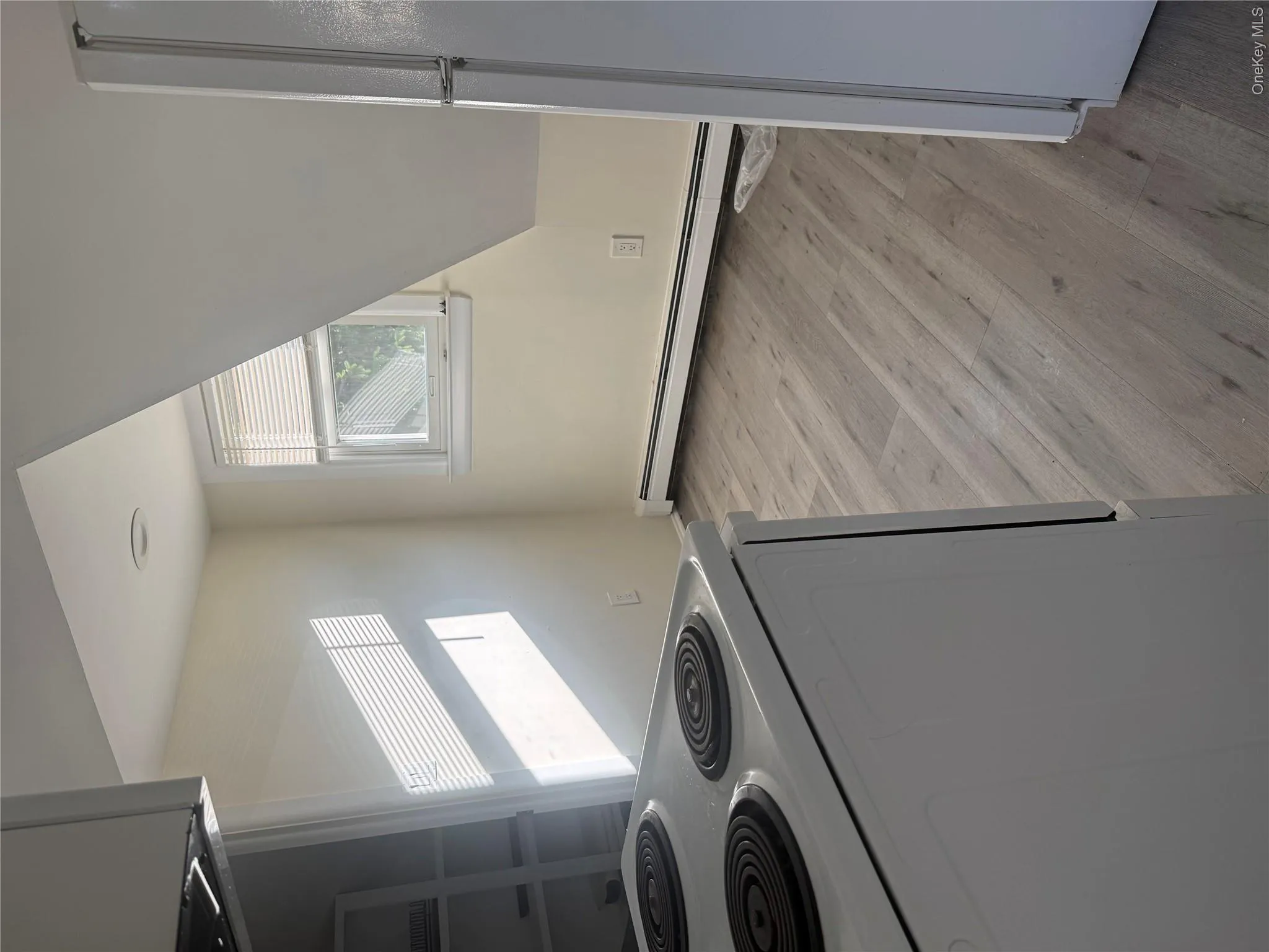 Wood-finish flooring, white window blinds, baseboard heating, recessed ceiling lighting, and a white electric range Wood-finish flooring, white window blinds, baseboard heating, recessed ceiling lighting, and a white electric range