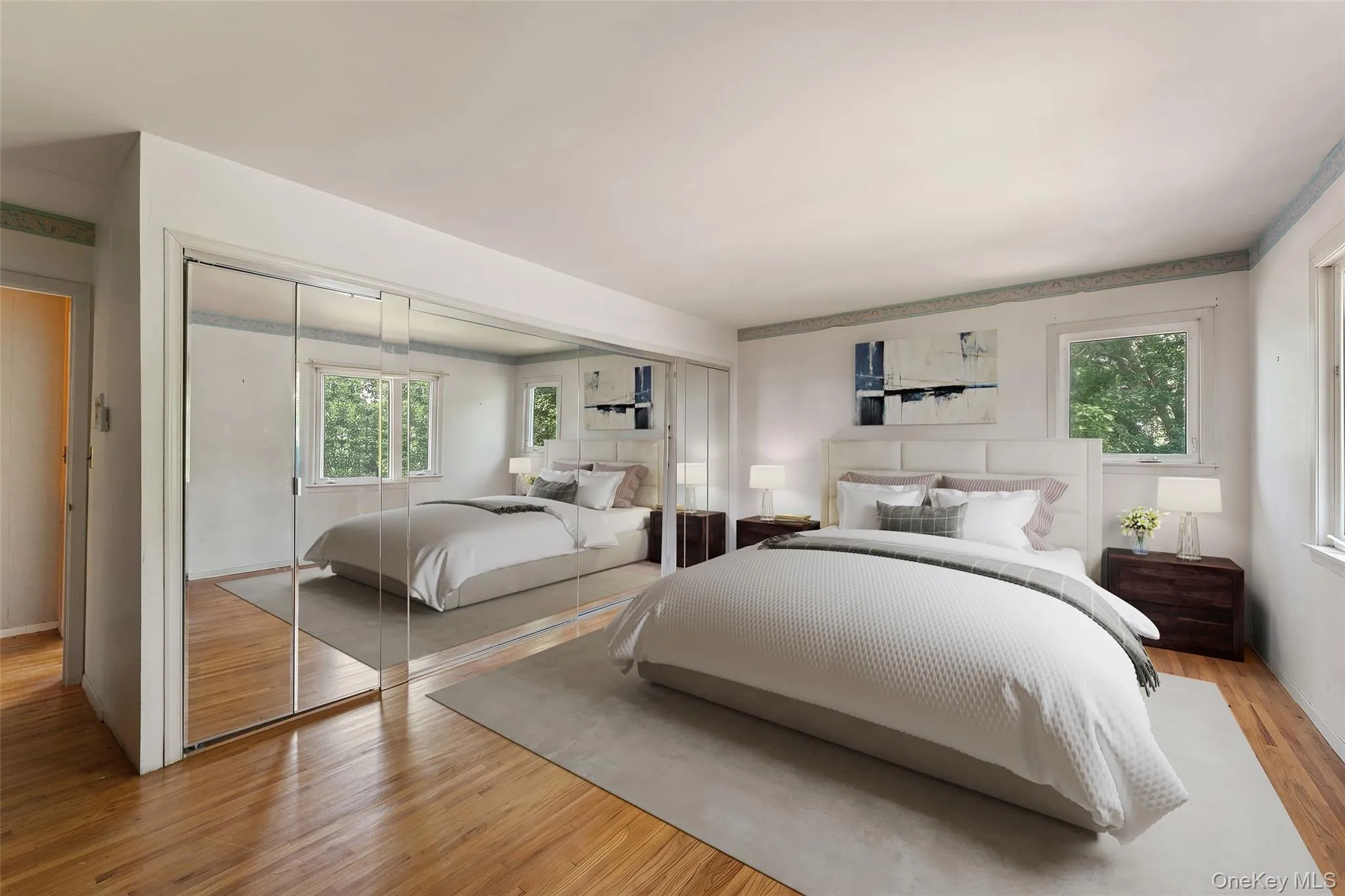 Primary Bedroom is virtually staged. Hardwood flooring, mirrored sliding closet doors, with multiple windows. Primary Bedroom is virtually staged. Hardwood flooring, mirrored sliding closet doors, with multiple windows.
