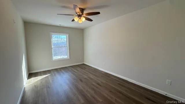 Empty room with ceiling fan and dark hardwood / wood-style floors Empty room with ceiling fan and dark hardwood / wood-style floors