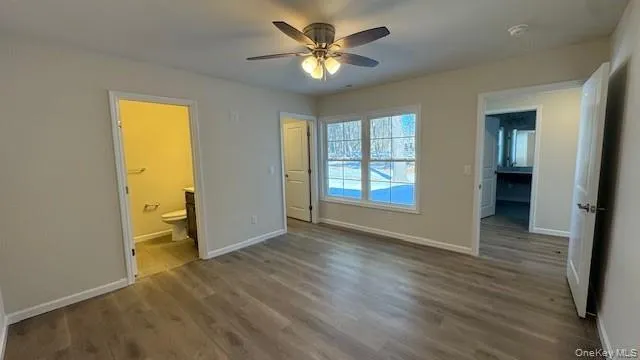 Unfurnished bedroom featuring ensuite bath, ceiling fan, and hardwood / wood-style flooring Unfurnished bedroom featuring ensuite bath, ceiling fan, and hardwood / wood-style flooring