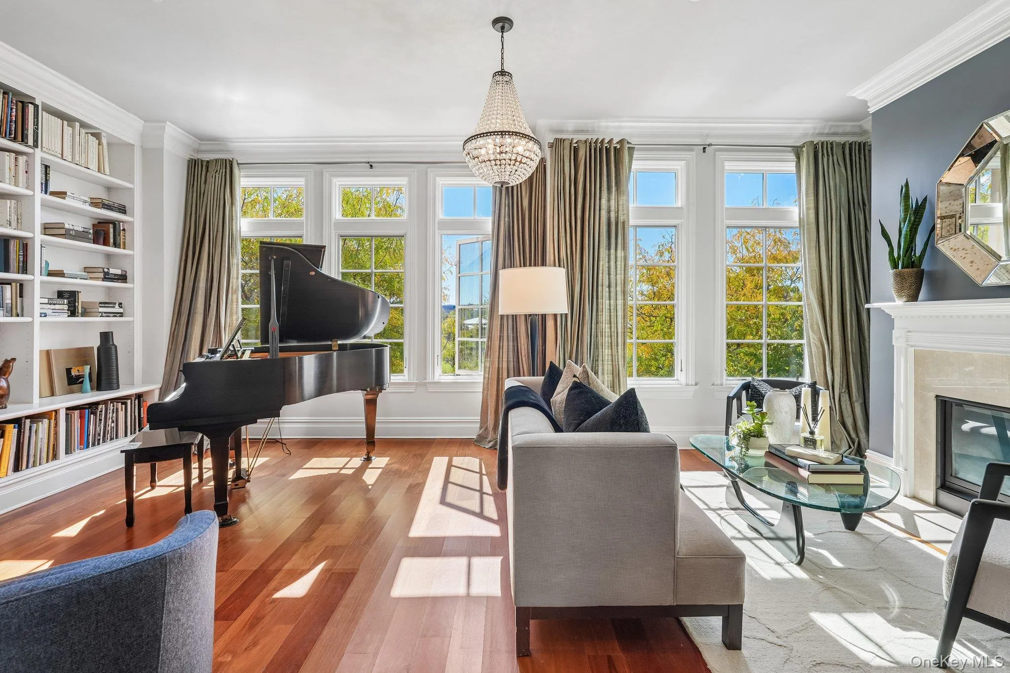 Hardwood-style flooring throughout, built-in shelving, fireplace with stone surround, crown molding, and a crystal chandelier Hardwood-style flooring throughout, built-in shelving, fireplace with stone surround, crown molding, and a crystal chandelier