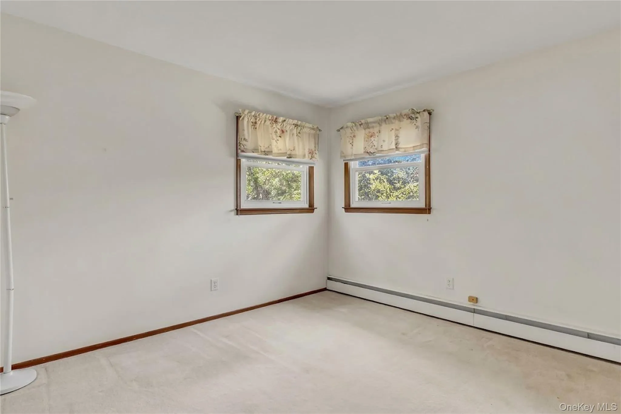 Neutral-toned interior featuring dual windows with wood trim and wall-to-wall carpeting Neutral-toned interior featuring dual windows with wood trim and wall-to-wall carpeting