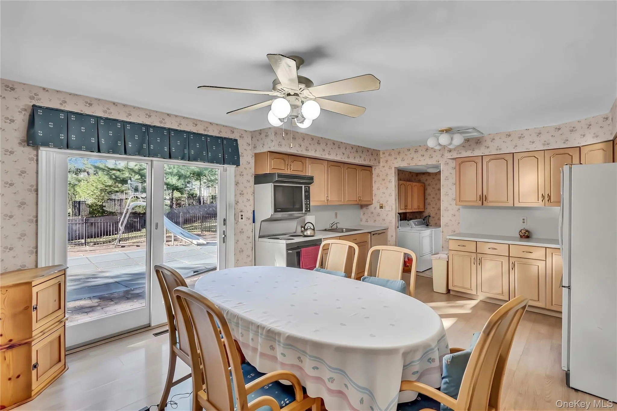 Kitchen featuring light-finish cabinetry, sliding glass doors, wood-finish flooring, and a ceiling-mounted light fixture Kitchen featuring light-finish cabinetry, sliding glass doors, wood-finish flooring, and a ceiling-mounted light fixture