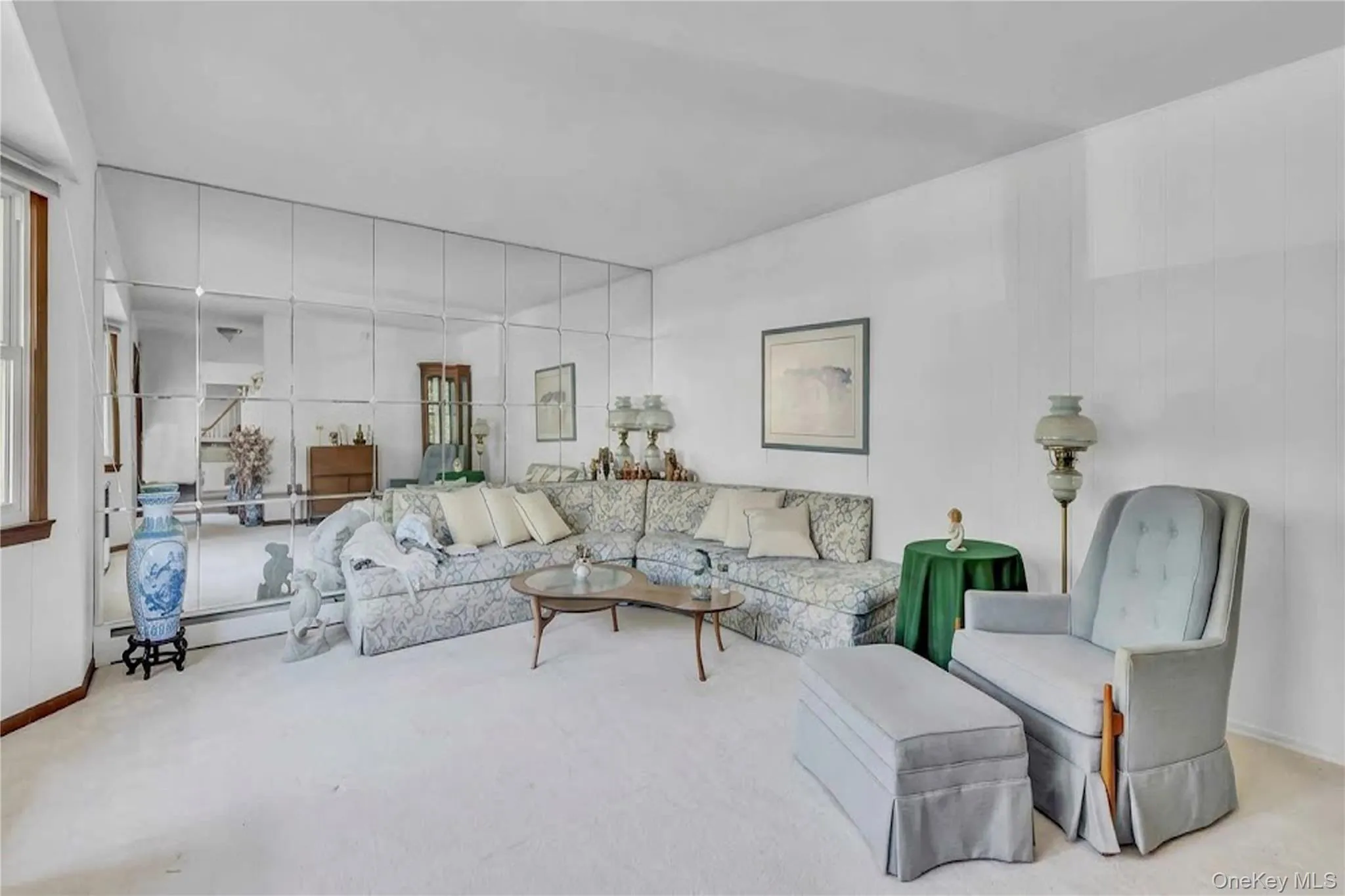 Living area featuring floor-to-ceiling grid-pattern mirrored walls and neutral carpeting Living area featuring floor-to-ceiling grid-pattern mirrored walls and neutral carpeting