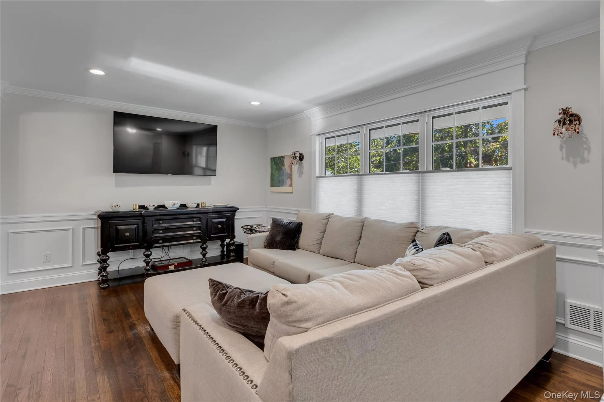 Hardwood flooring with a satin finish, white wall paneling, recessed lighting, and crown molding Hardwood flooring with a satin finish, white wall paneling, recessed lighting, and crown molding