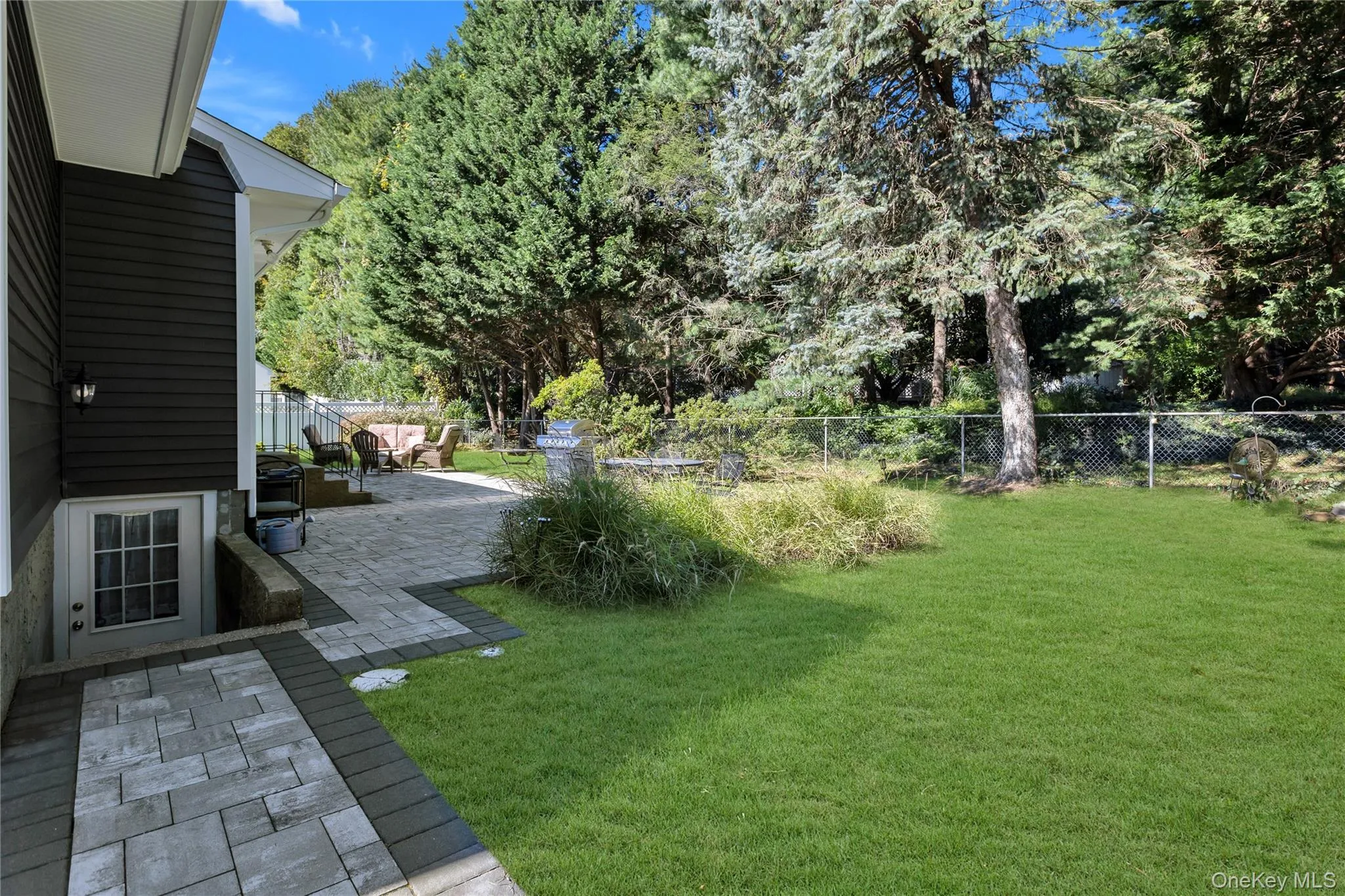 Expansive yard featuring a manicured lawn, mature trees, and a spacious paver patio Expansive yard featuring a manicured lawn, mature trees, and a spacious paver patio