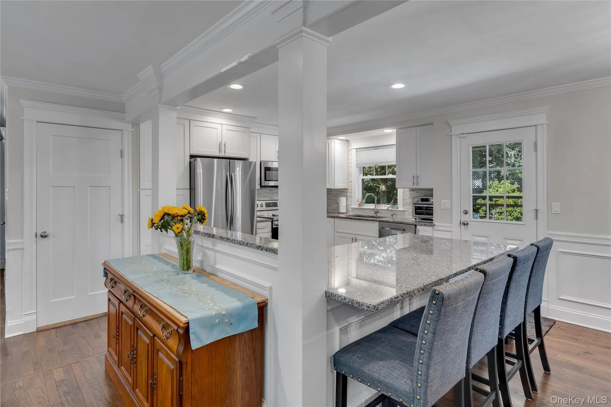 Bright, open-concept kitchen and dining area featuring white cabinetry, stainless steel appliances, quartz countertops, and a large center island with wood-finish base and seating for multiple guests Bright, open-concept kitchen and dining area featuring white cabinetry, stainless steel appliances, quartz countertops, and a large center island with wood-finish base and seating for multiple guests