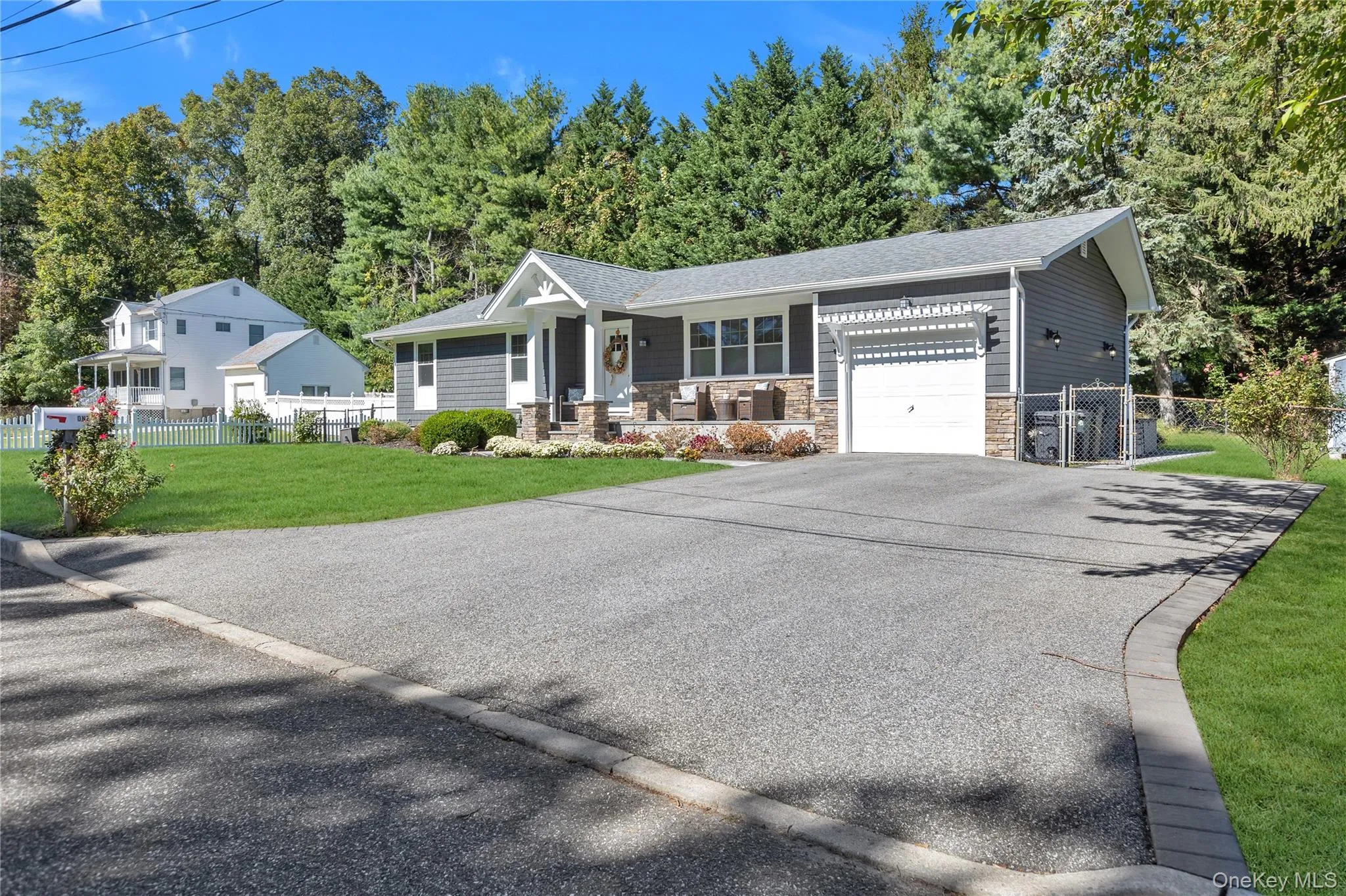 Ranch-style exterior with gray horizontal siding and stone accents. Double wide driveway with access to one car attached garage, Ranch-style exterior with gray horizontal siding and stone accents. Double wide driveway with access to one car attached garage,