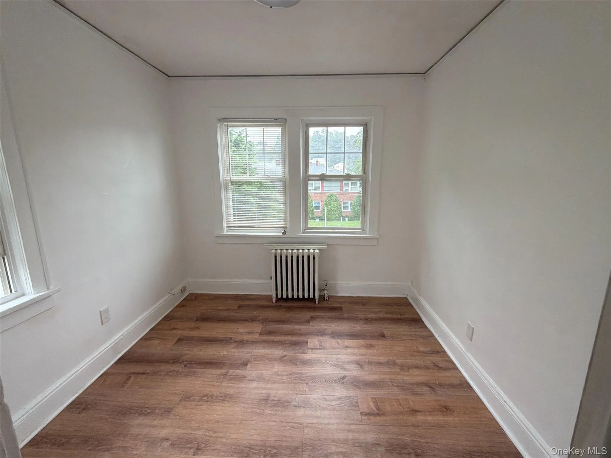 bedroom 2 Wood-finish flooring, white walls, double-hung windows, and a radiator bedroom 2 Wood-finish flooring, white walls, double-hung windows, and a radiator
