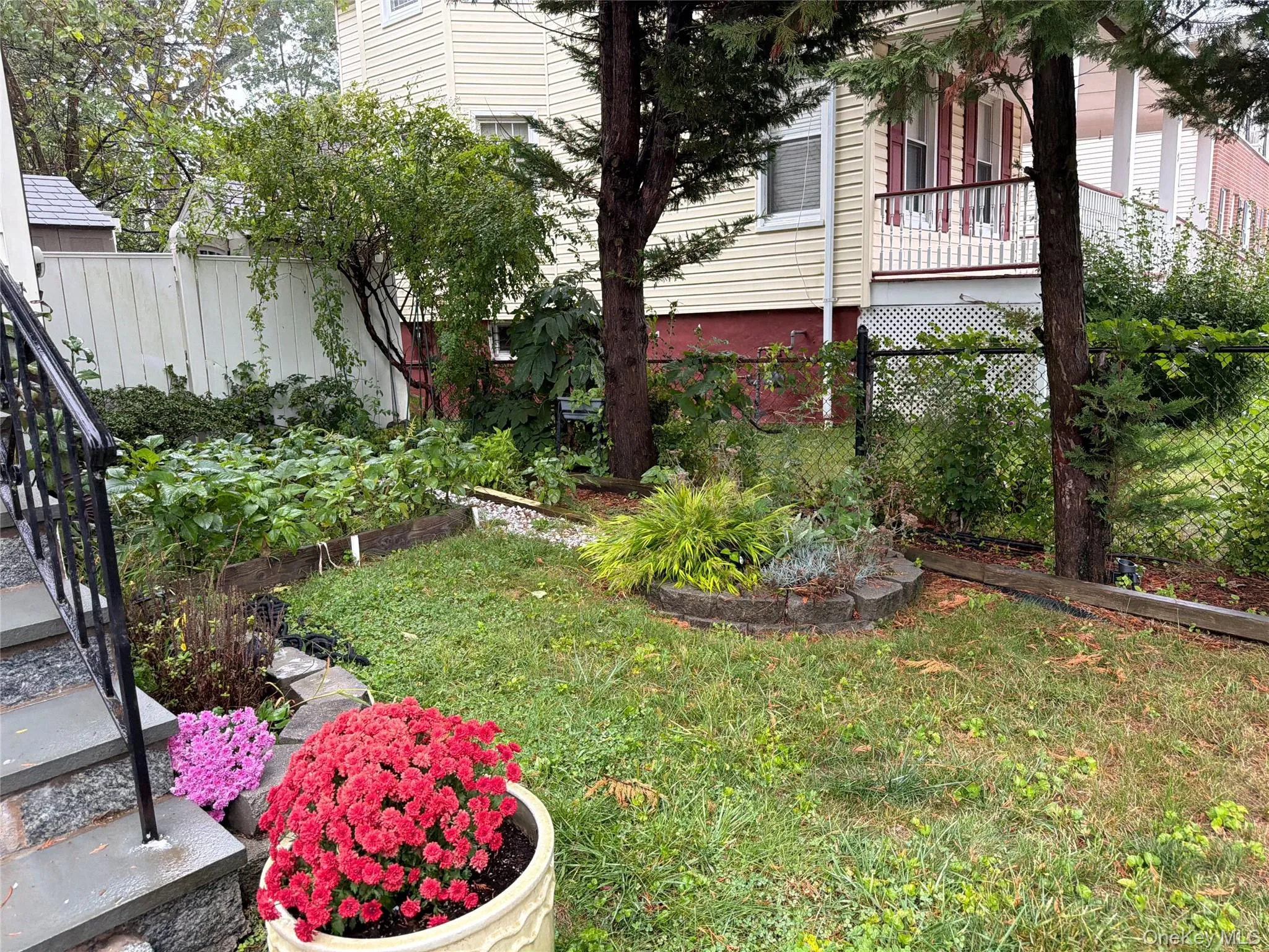 Landscaped yard with stone-edged garden beds, established trees, and a privacy fence Landscaped yard with stone-edged garden beds, established trees, and a privacy fence