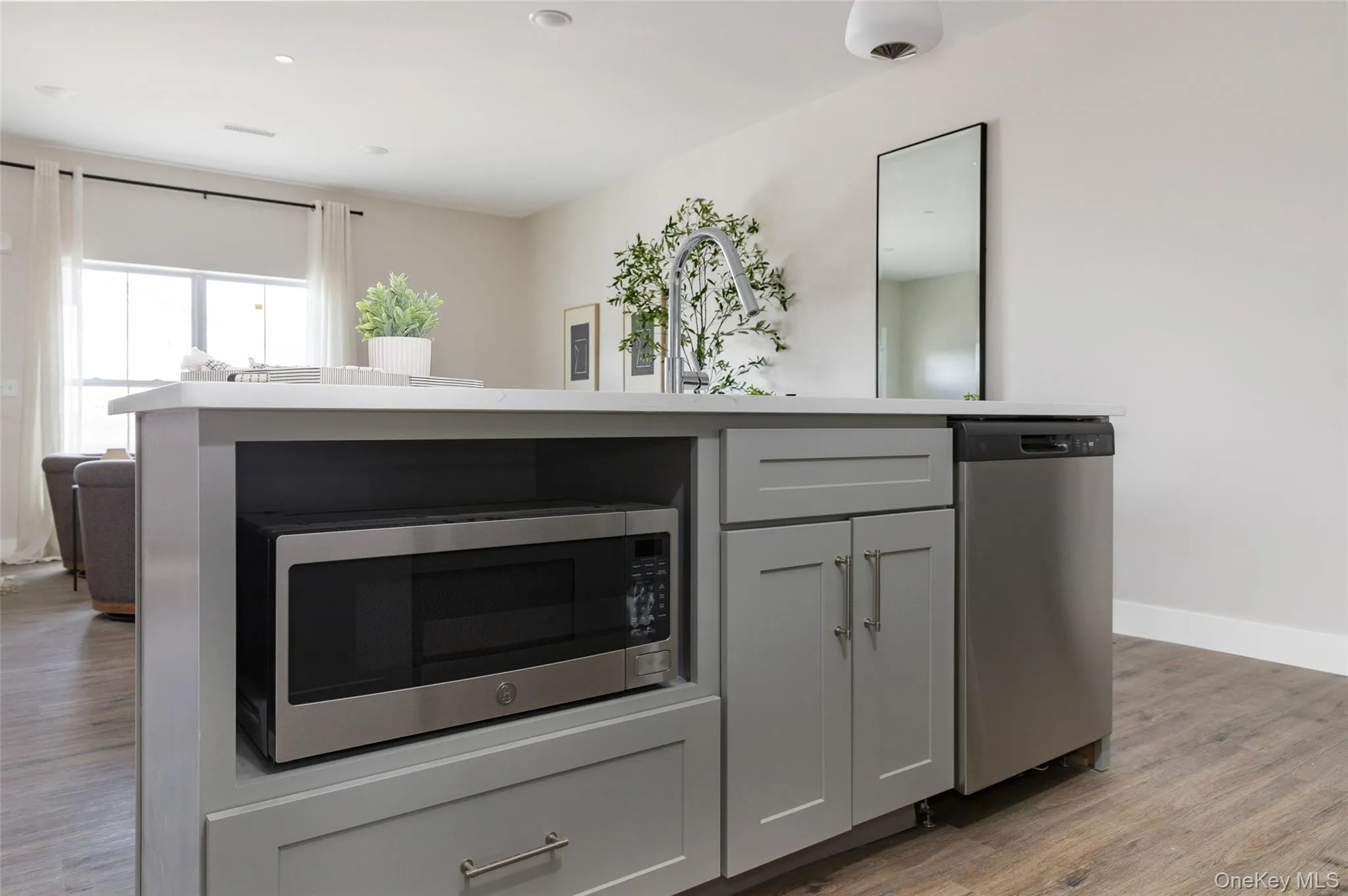 Kitchen island featuring a single-basin sink, stainless steel faucet, stainless steel dishwasher, built-in microwave, and shaker-style cabinetry Kitchen island featuring a single-basin sink, stainless steel faucet, stainless steel dishwasher, built-in microwave, and shaker-style cabinetry
