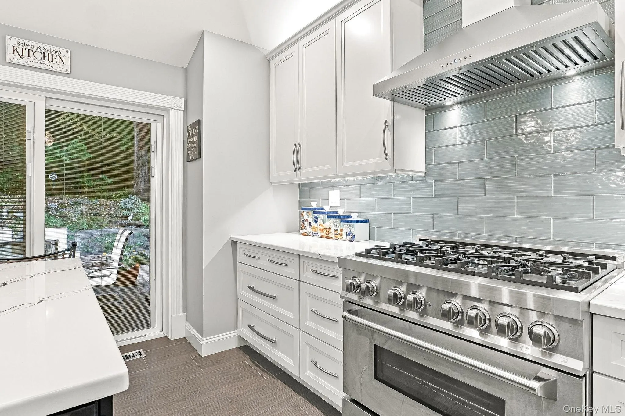 Stainless steel range with a ventilation hood, white cabinetry, tile backsplash, and light-toned countertops Stainless steel range with a ventilation hood, white cabinetry, tile backsplash, and light-toned countertops