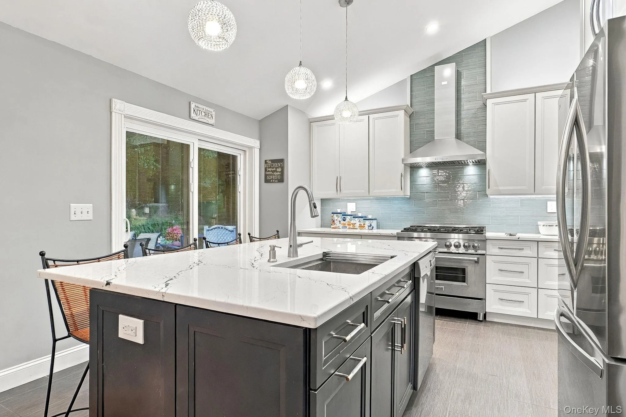 Gourmet kitchen featuring a center island with sink, white countertops, built-in stainless steel appliances, and light wood-finish flooring Gourmet kitchen featuring a center island with sink, white countertops, built-in stainless steel appliances, and light wood-finish flooring