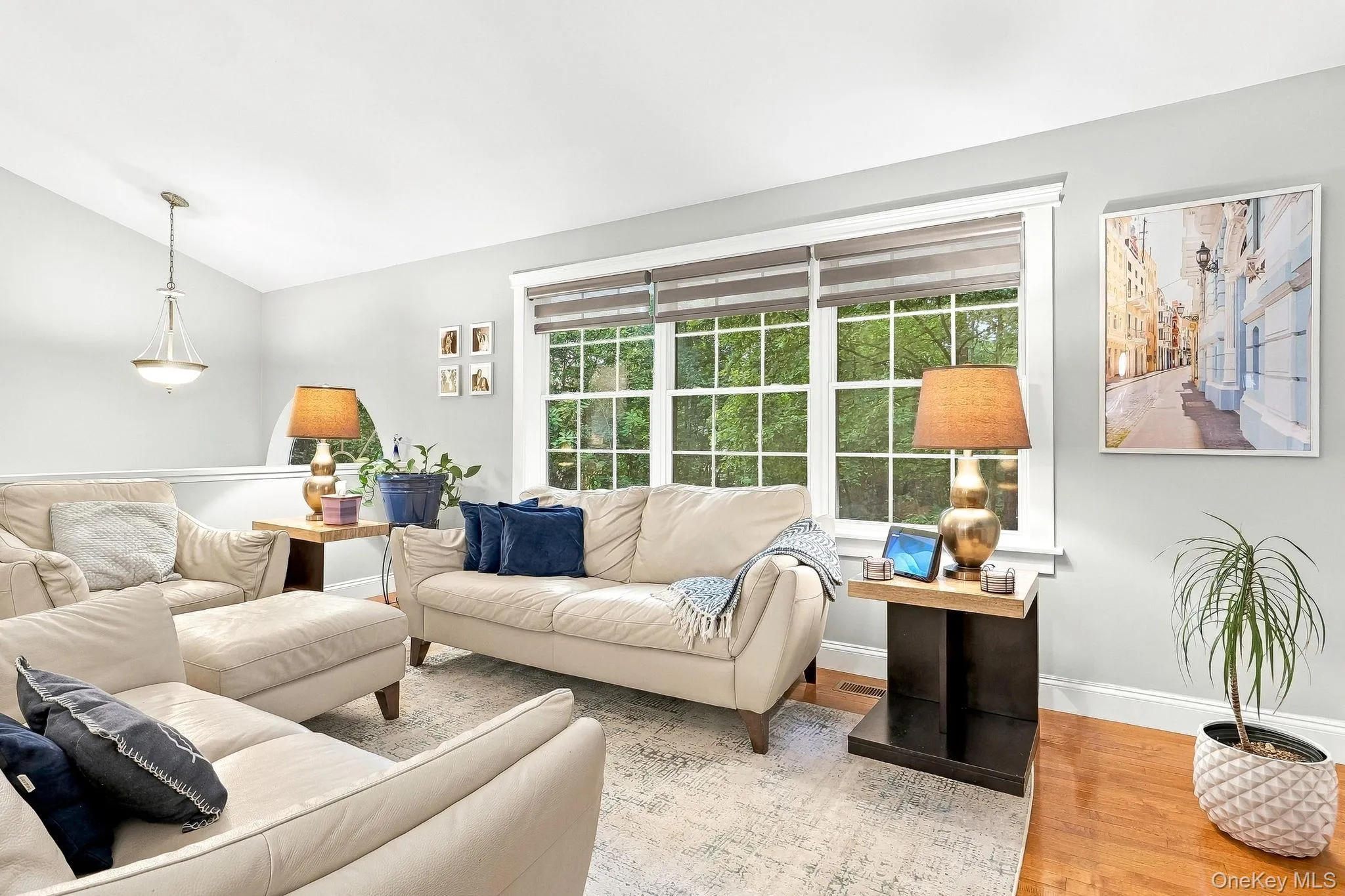 Spacious living area featuring large windows, wood flooring, and a decorative pendant light fixture in foyer area. Spacious living area featuring large windows, wood flooring, and a decorative pendant light fixture in foyer area.