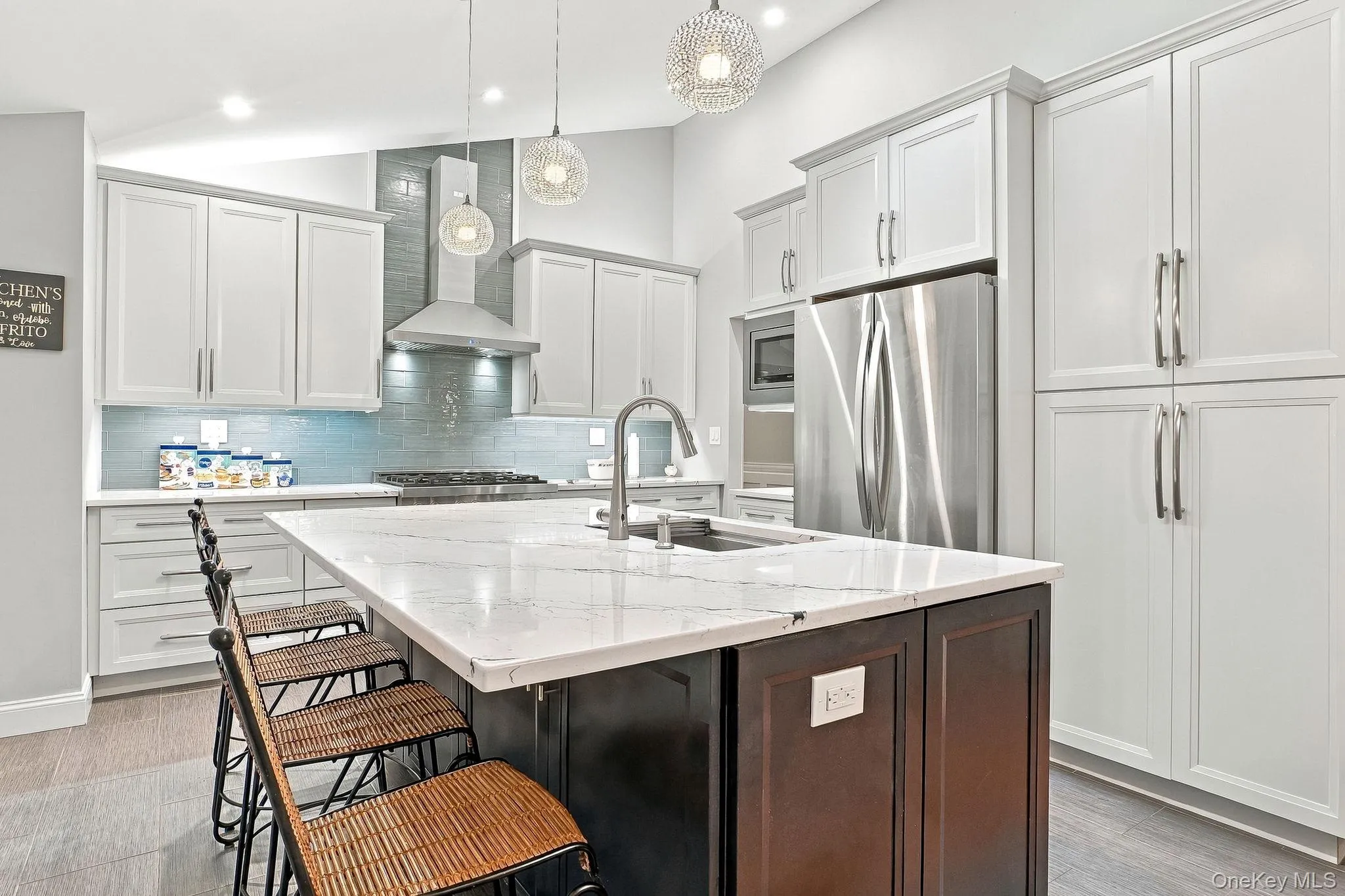 Kitchen featuring a central island with a Quartz countertop, white shaker cabinetry, stainless steel appliances, and a tile backsplash Kitchen featuring a central island with a Quartz countertop, white shaker cabinetry, stainless steel appliances, and a tile backsplash